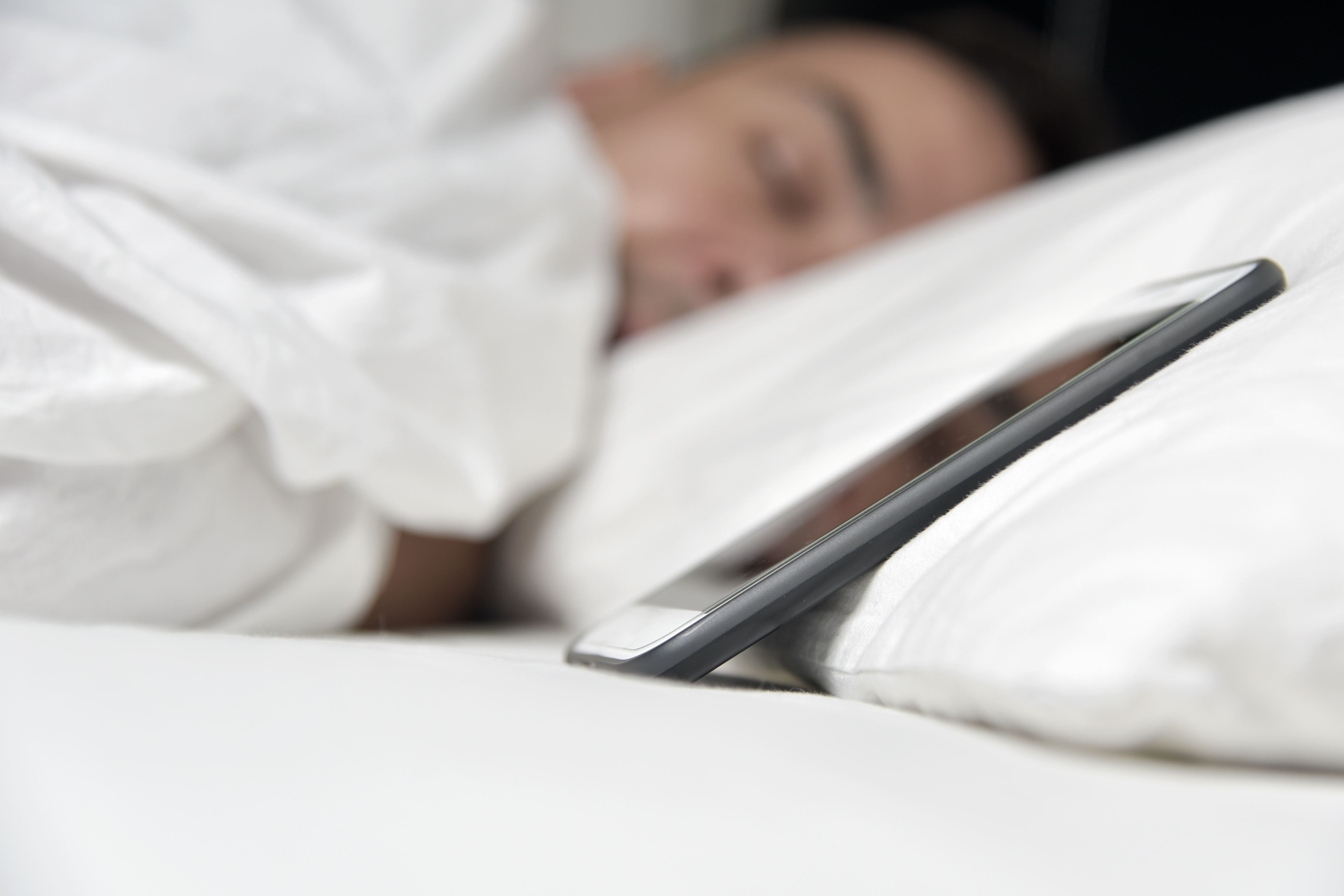 young man in bed close to his smartphone