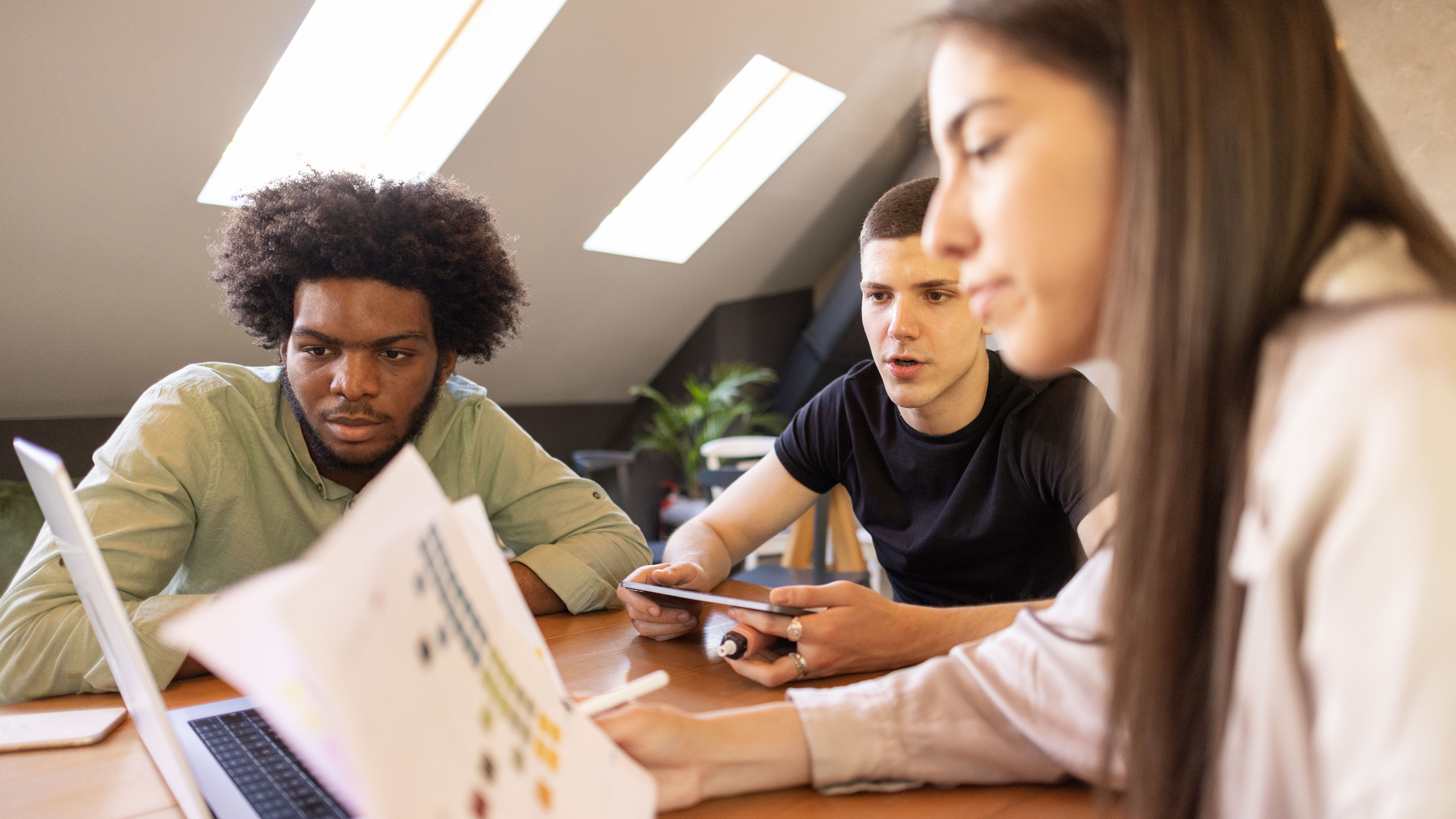 Multiracial group of young people, at the coffee shop, brainstorming new ways of investments