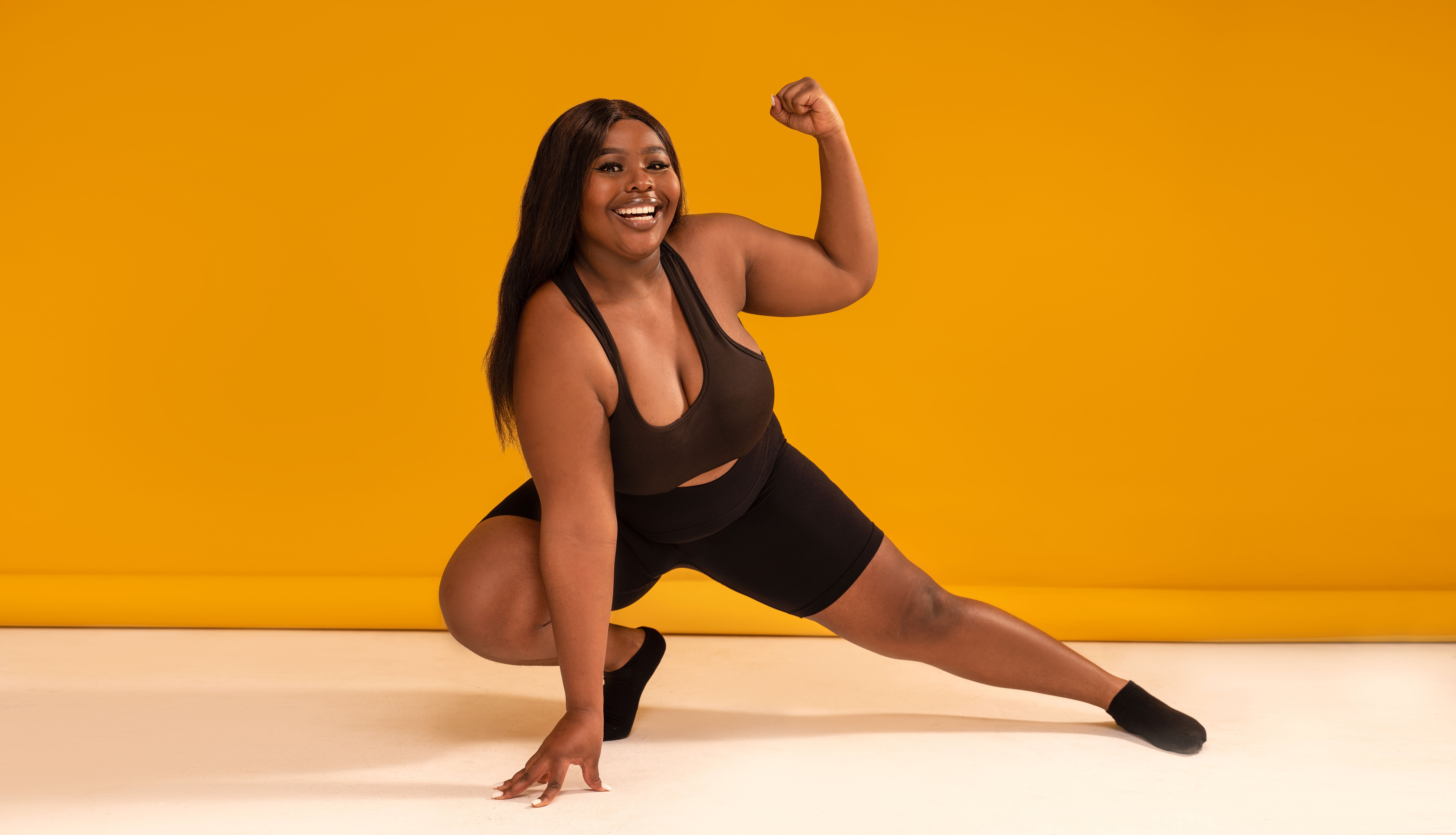 Happy plus size woman posing in sporty black fashionable clothes, smiling to the camera. Sports and weight loss concept. Full length photo. Happy plus size woman posing in sporty black fashionable clothes, smiling to the camera. Sports and weight loss concept. Full length photo.