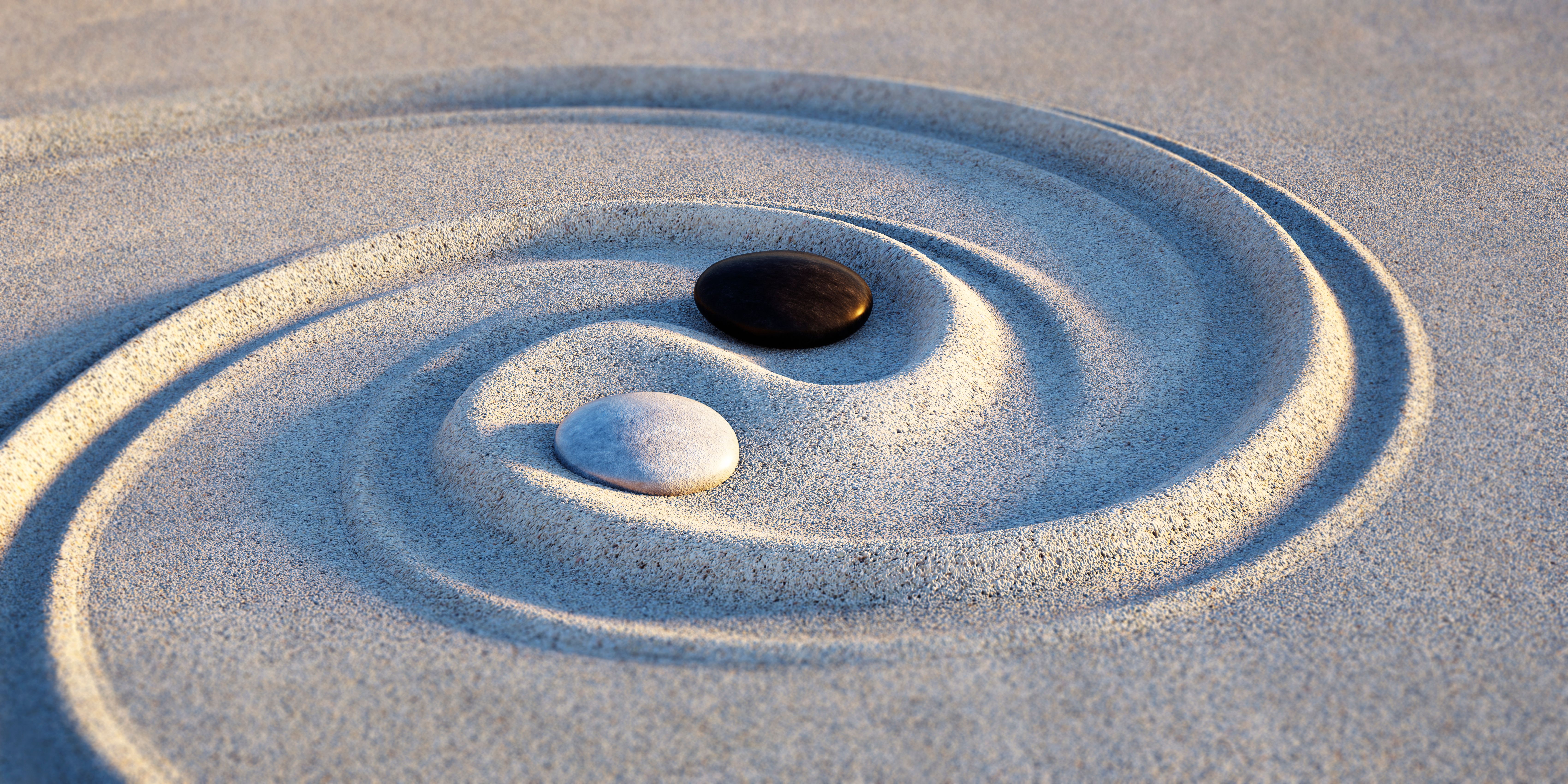 Yin Yang Motive made of stones and lines in the sand