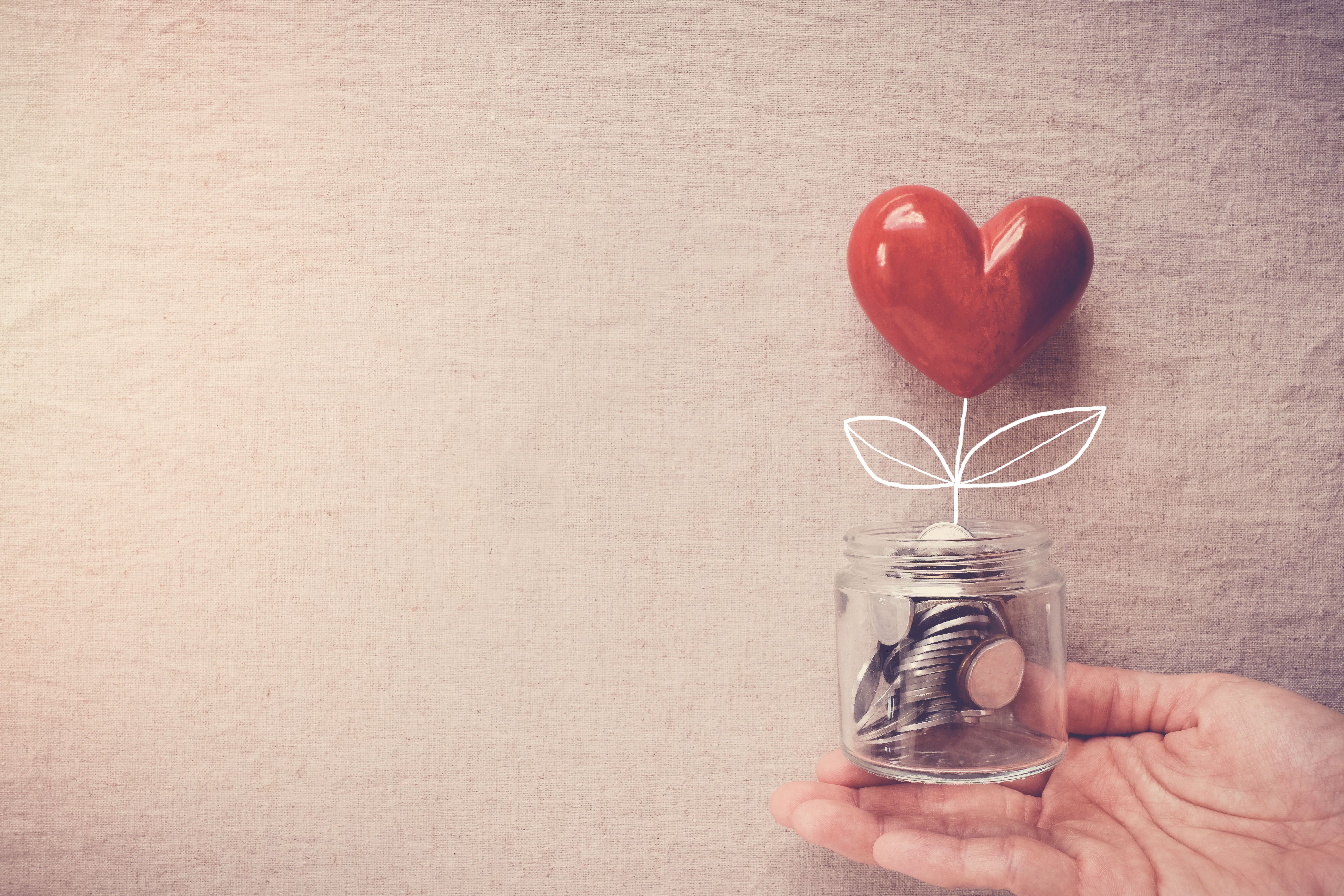 Hand holding a jar of heart tree growing on money coins, social responsibility and donation concept Hand holding a jar of heart tree growing on money coins, social responsibility and donation concept