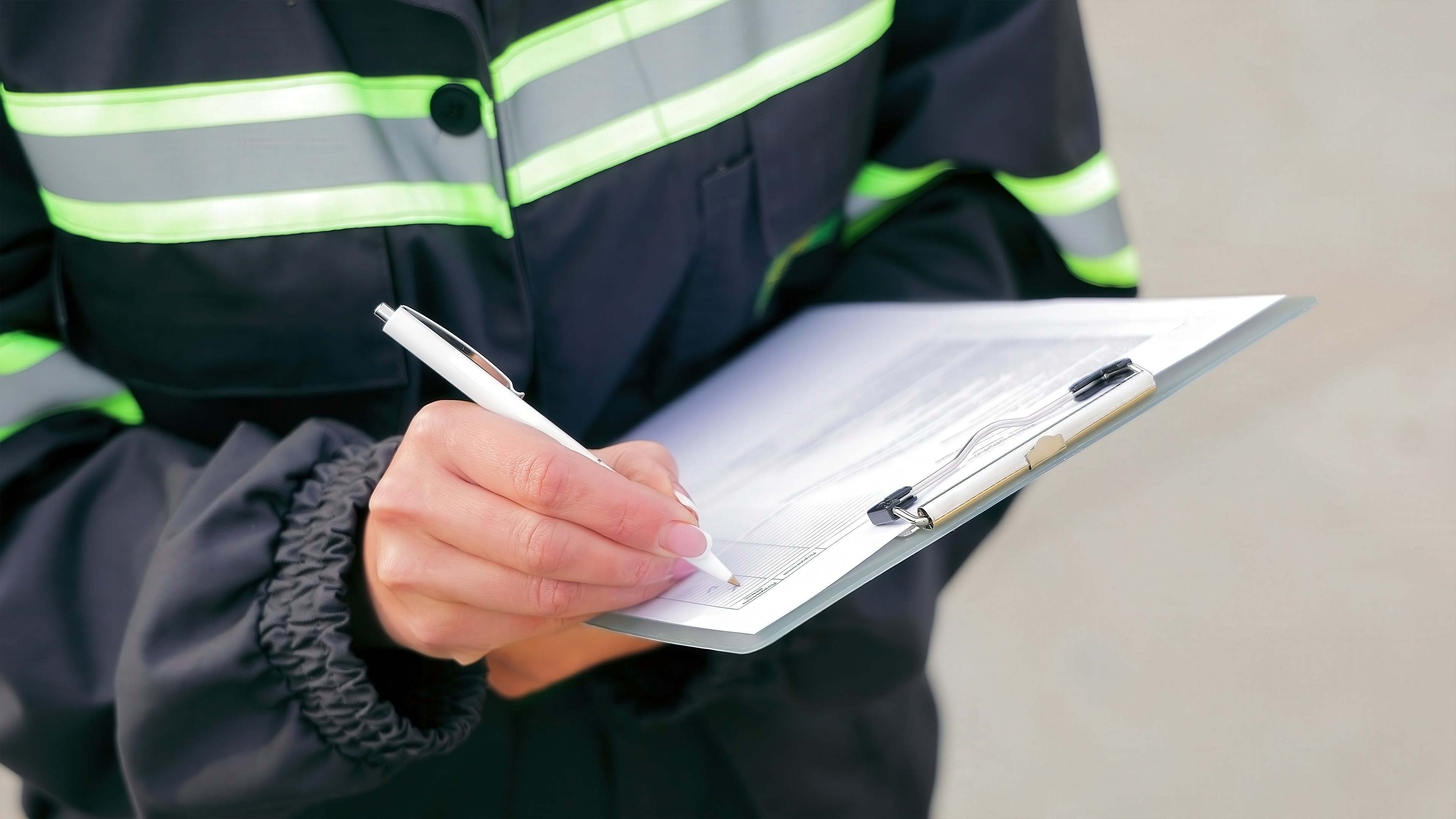 Worker Writing on Clipboard for Inspection. Close-up of a worker in reflective safety gear writing on a clipboard, documenting information during an inspection or checklist process. Worker Writing on Clipboard for Inspection. Close-up of a worker in reflective safety gear writing on a clipboard, documenting information during an inspection or checklist process.