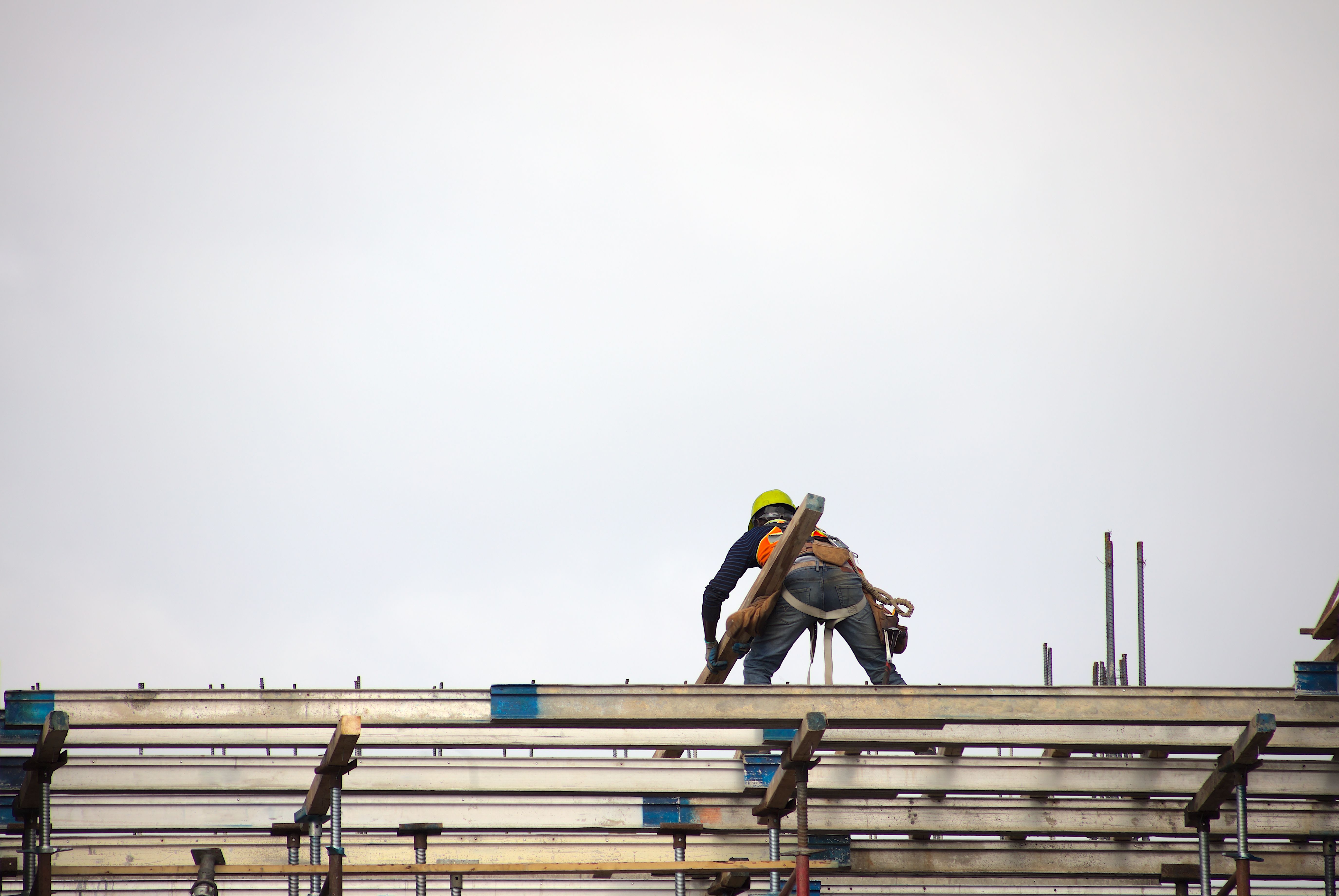 man at work construction site worker holding beam on roof structure building