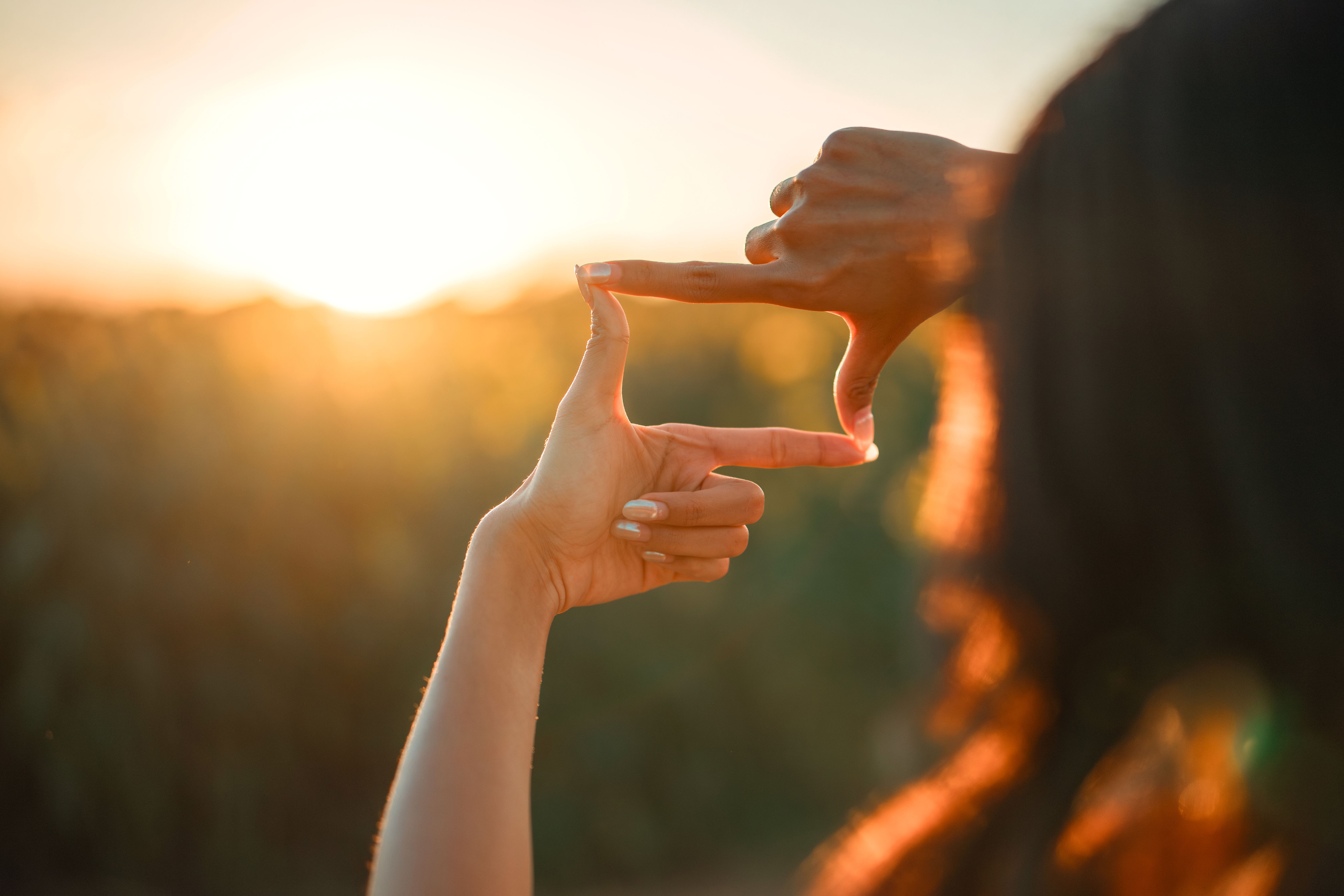 Closeup of woman hands making frame gesture with sunset, Female capturing the sunrise. Future planning concept. Closeup of woman hands making frame gesture with sunset, Female capturing the sunrise. Future planning concept.