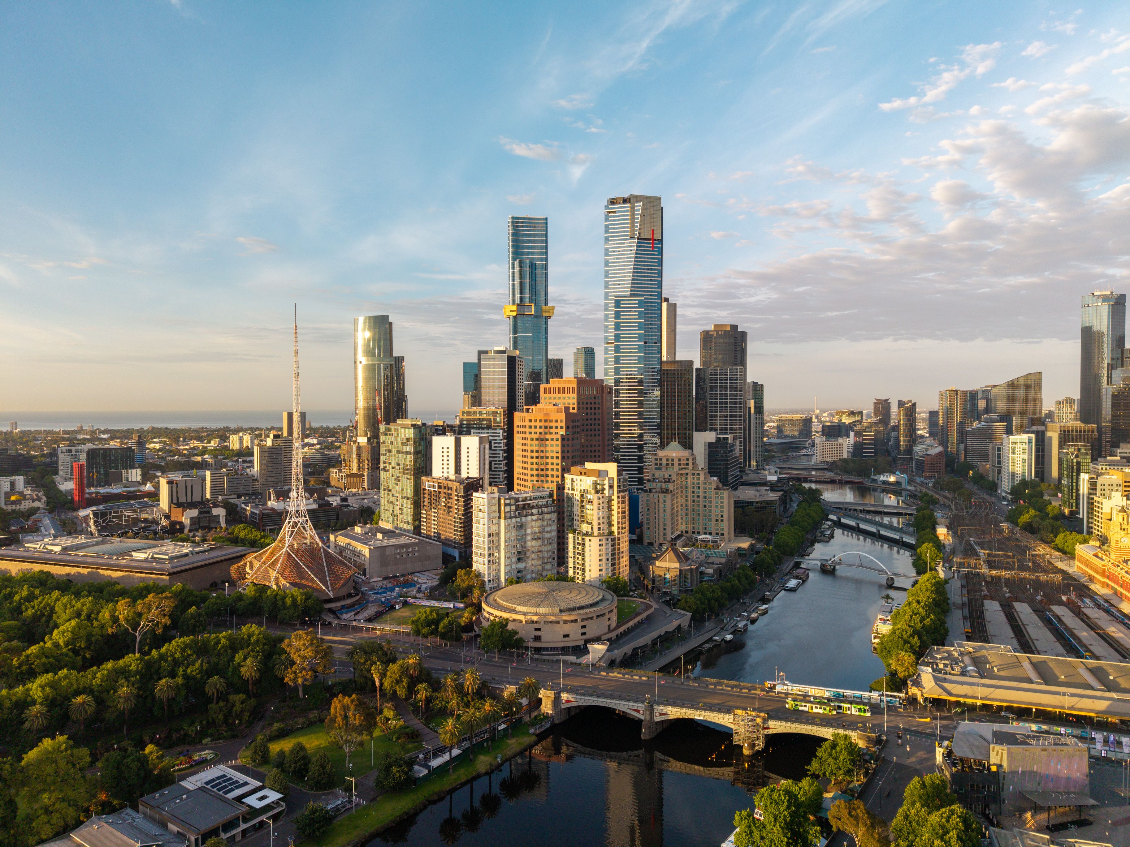 Melbourne's expansive urban landscape featuring towering skyscrapers, the winding Yarra River, bridges, and green spaces bathed in golden light. Melbourne's expansive urban landscape featuring towering skyscrapers, the winding Yarra River, bridges, and green spaces bathed in golden light.