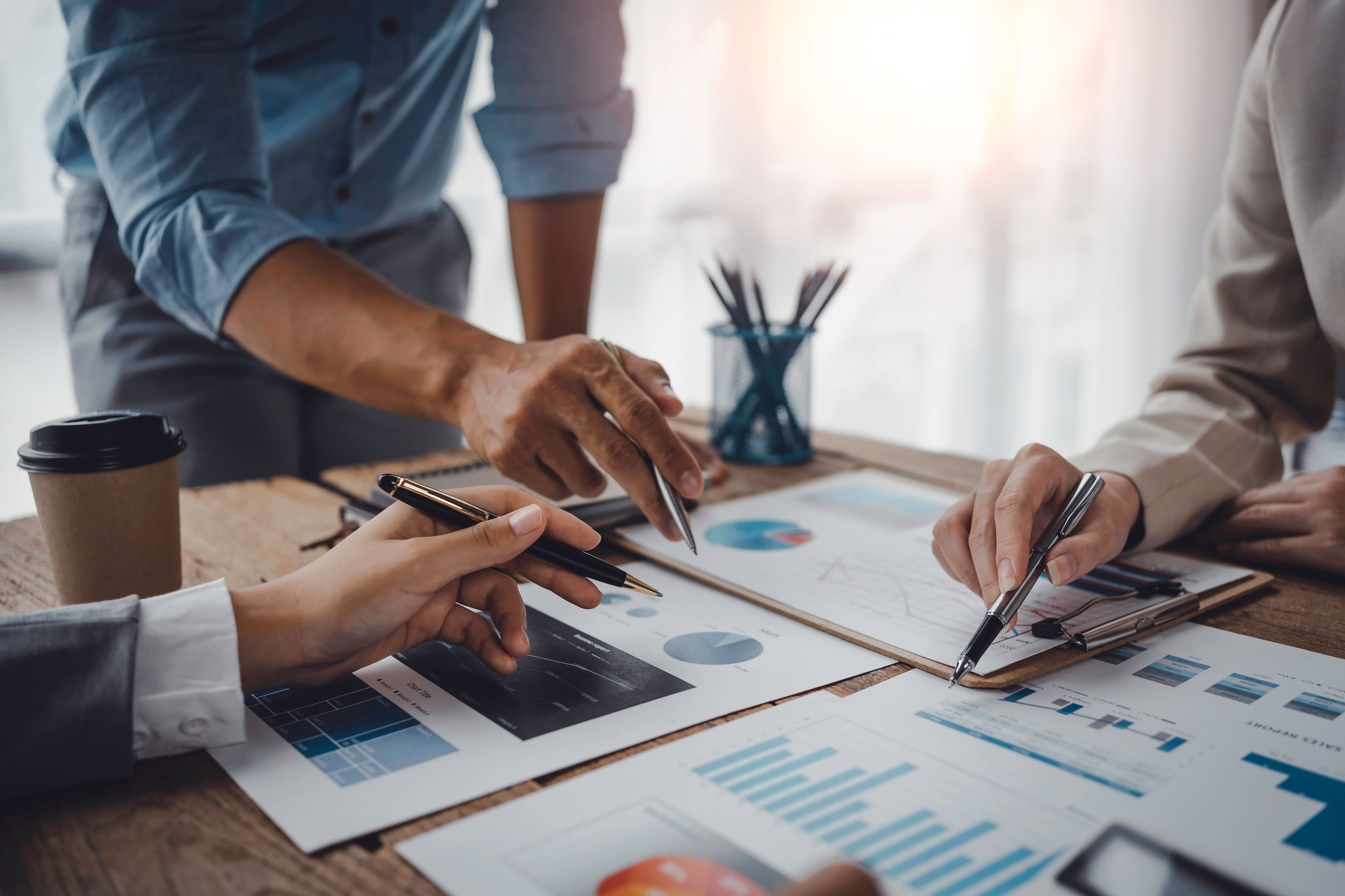 Business people pointing to a graph to analyze market data Net profit balance sheet to plan new marketing strategies to extend existing products.