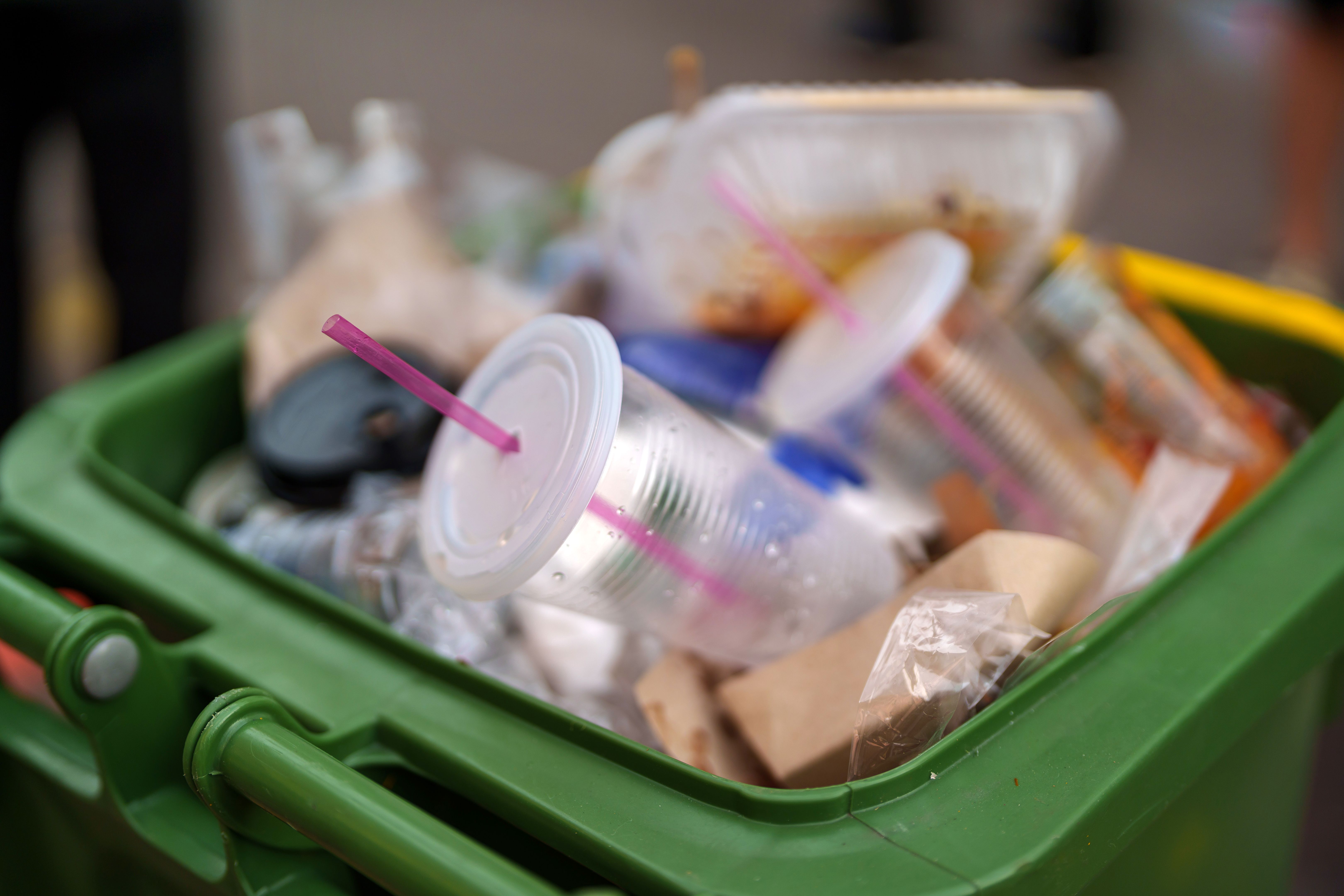 The green dustbin by the street is overflowing with rubbish The green dustbin by the street is overflowing with rubbish