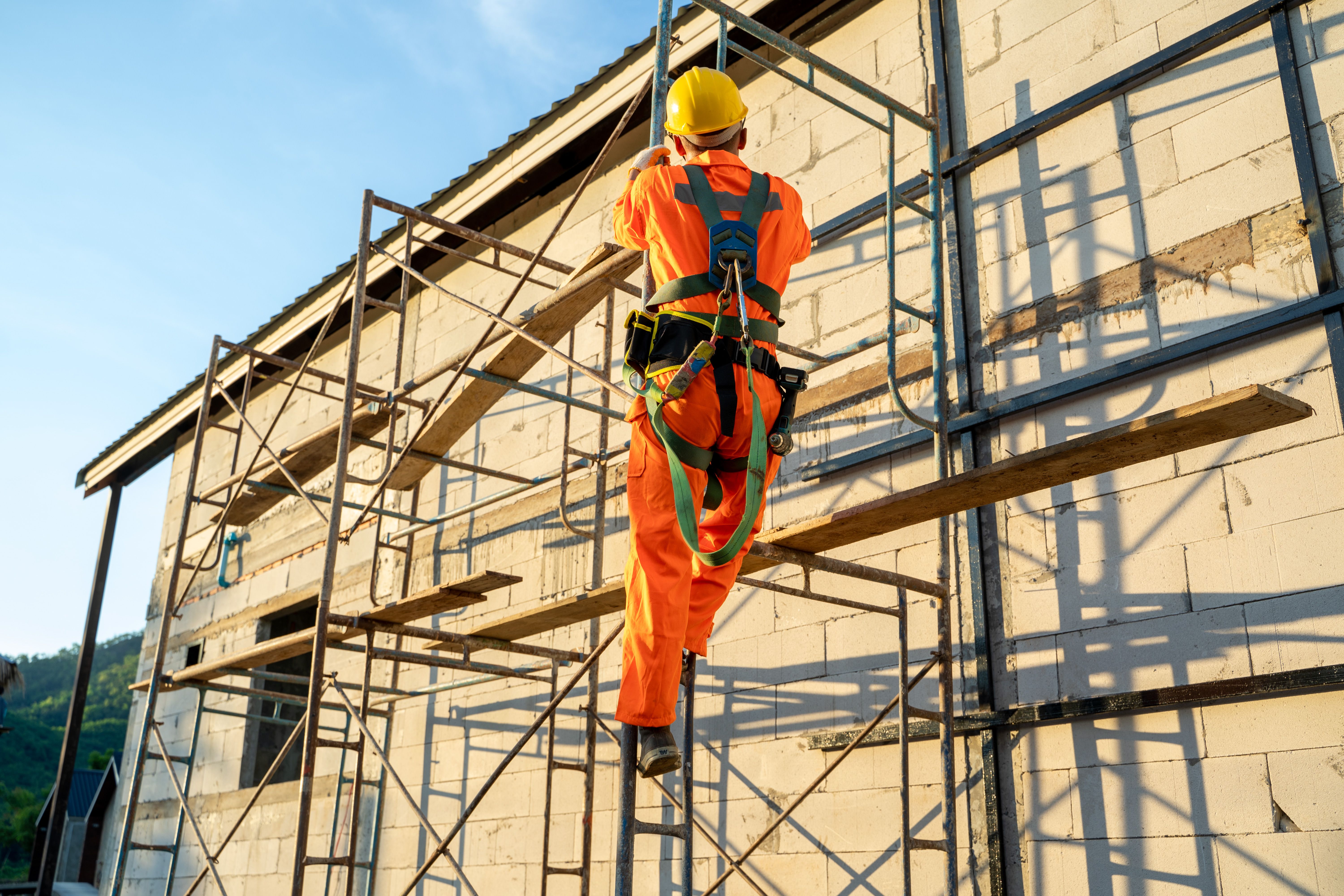 Construction worker wearing safety harness belt during working at high place.