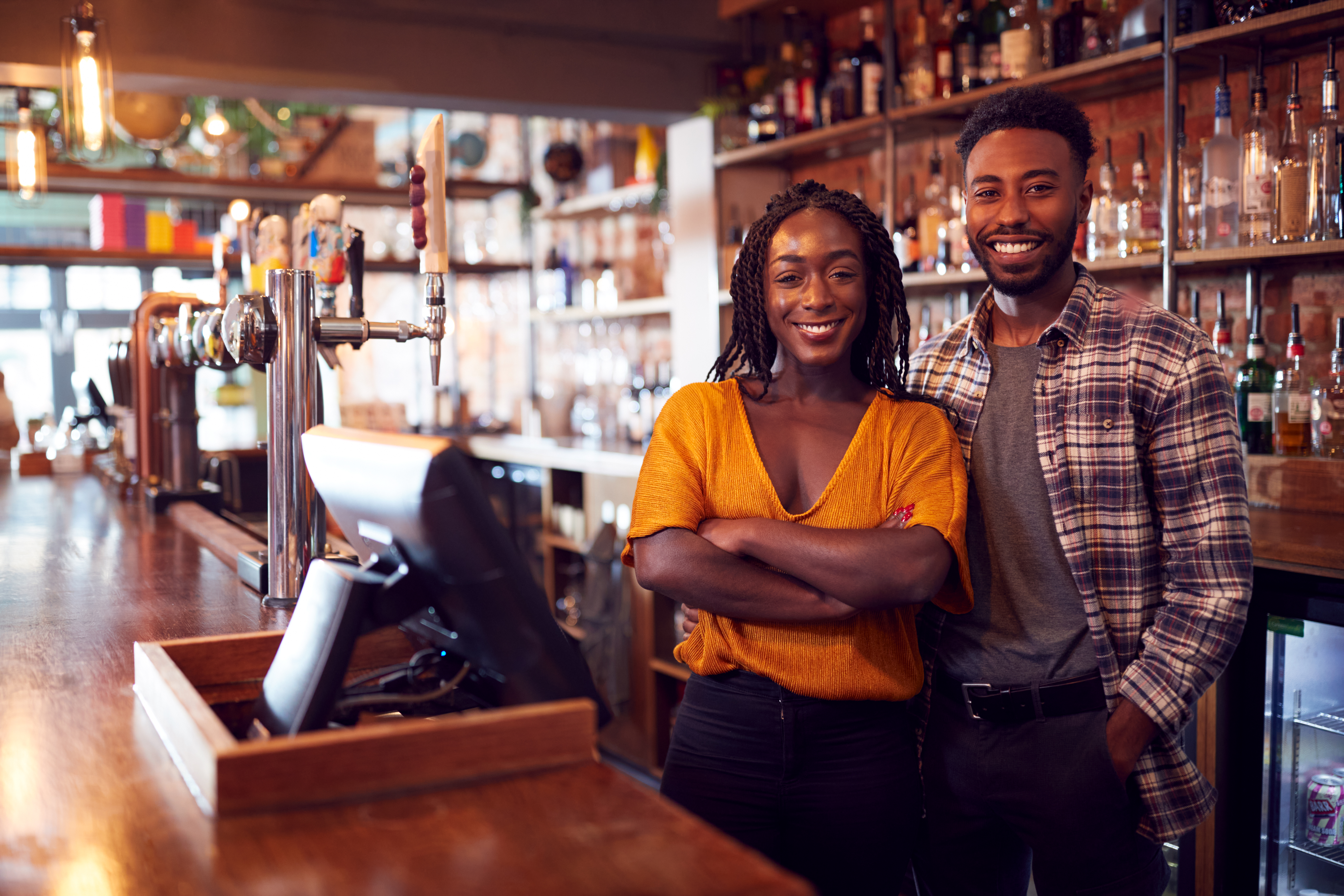 Portrait Of Smiling Couple Owning Bar Standing Behind Counter