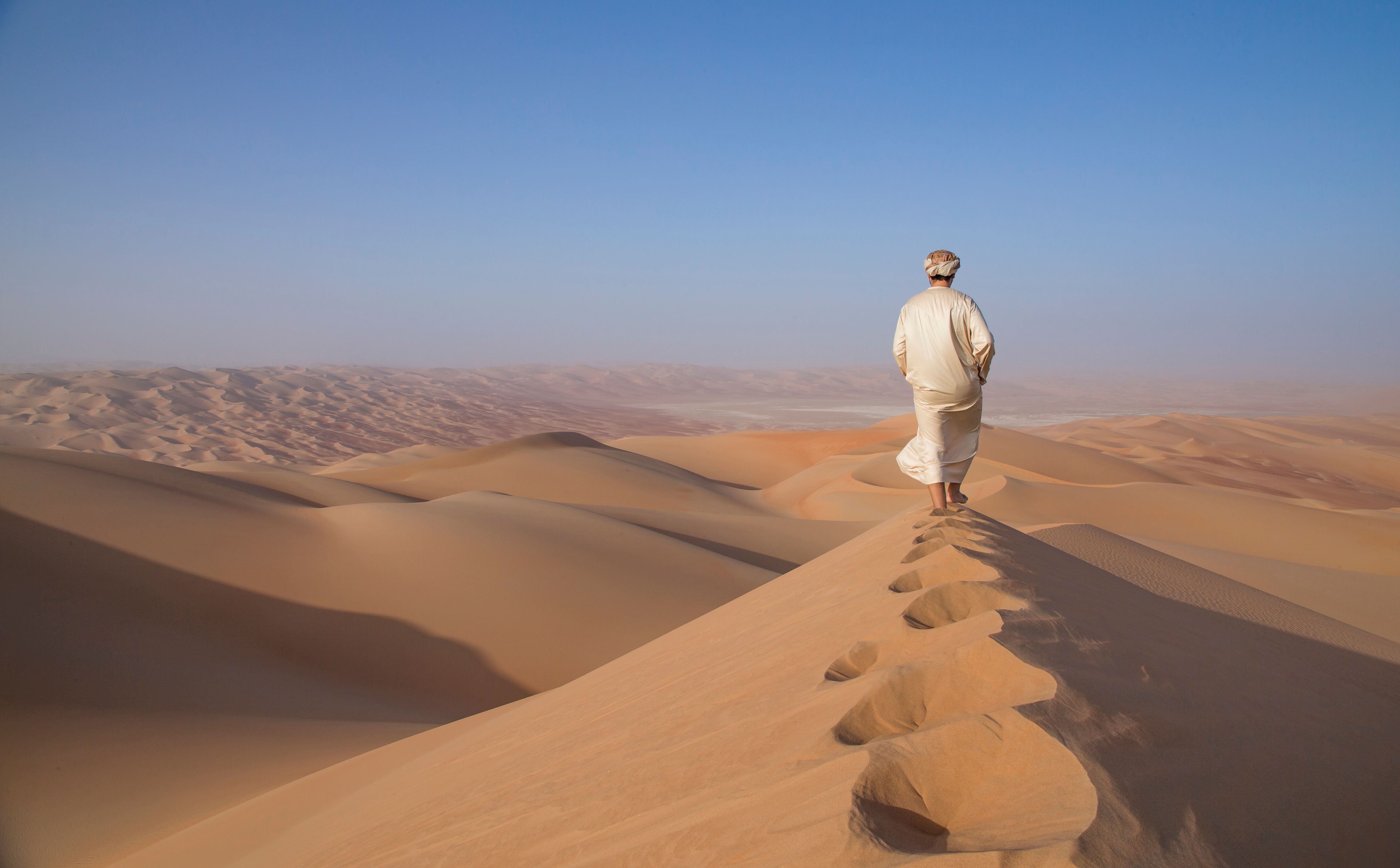 Man in kandura in a desert at sunrise Man in kandura in a desert at sunrise