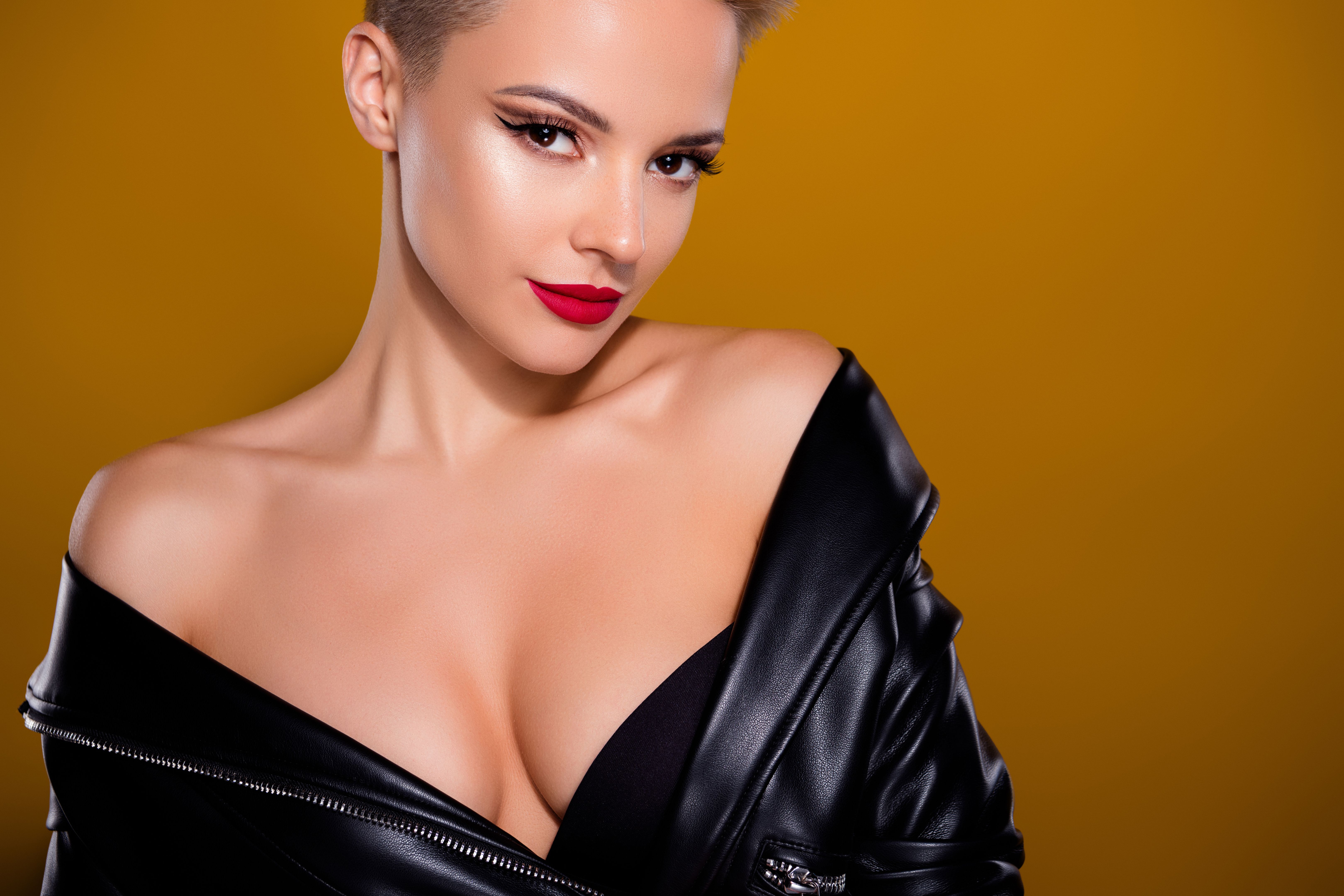 Photo of blonde haired woman wear black leather blazer look in camera isolated brown yellow background