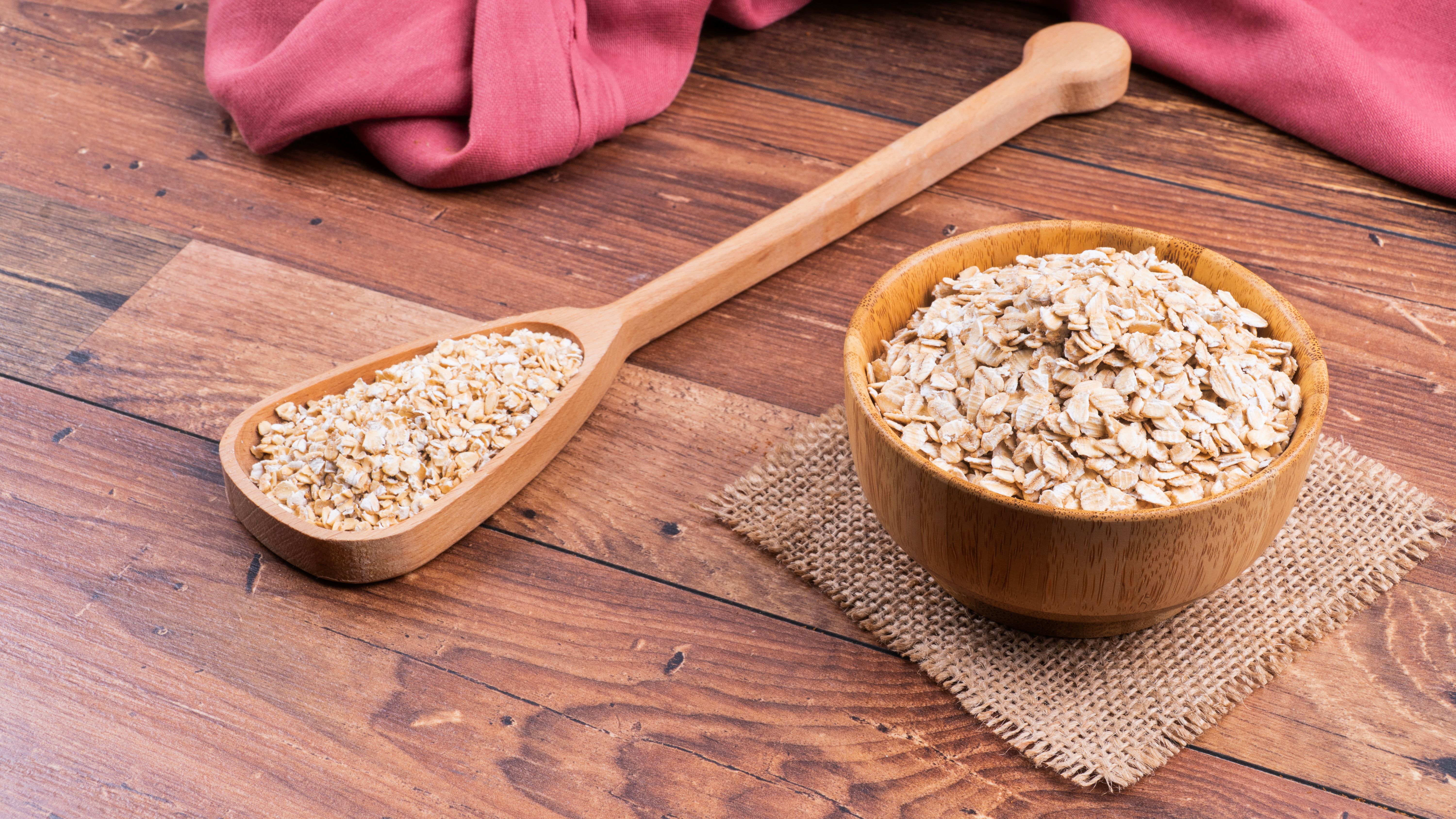 Oat flakes in a spoon on wooden surface