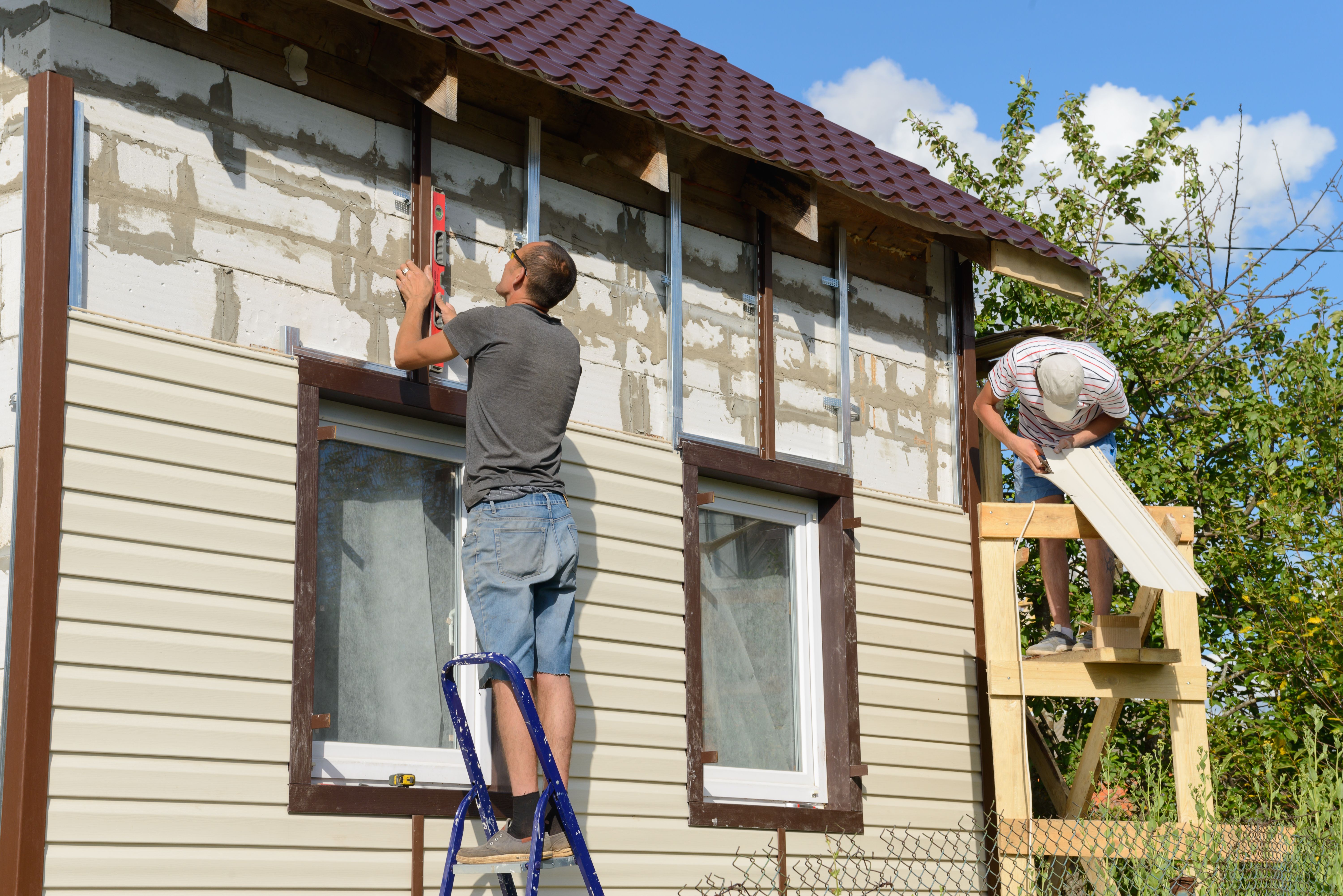 August 6, 2017: two workers polish the apartment building with vinyl siding. Moskakassy. Chuvashy. Russia.