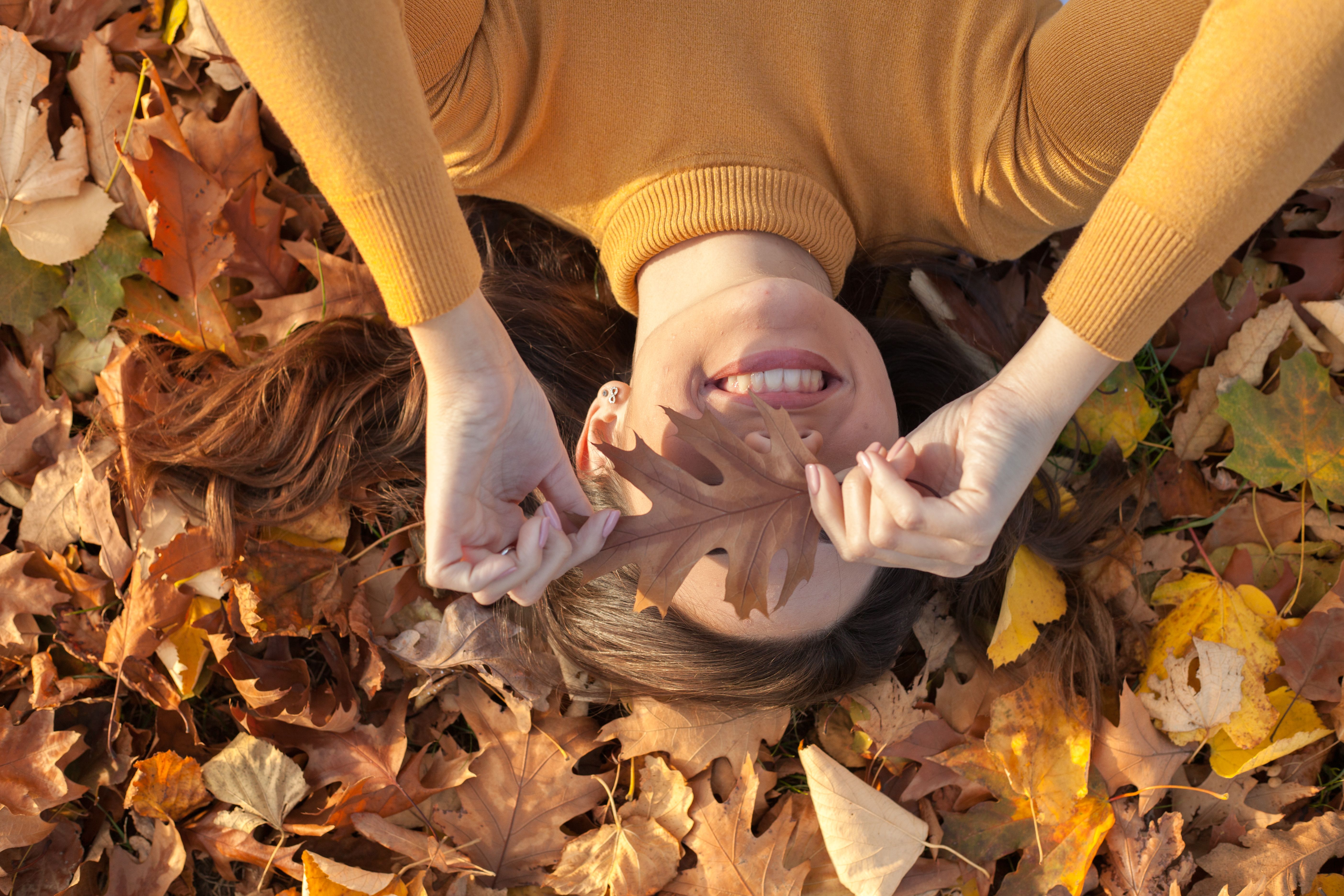 Young woman having fun in the park with leaf on her face Young woman having fun in the park with leaf on her face