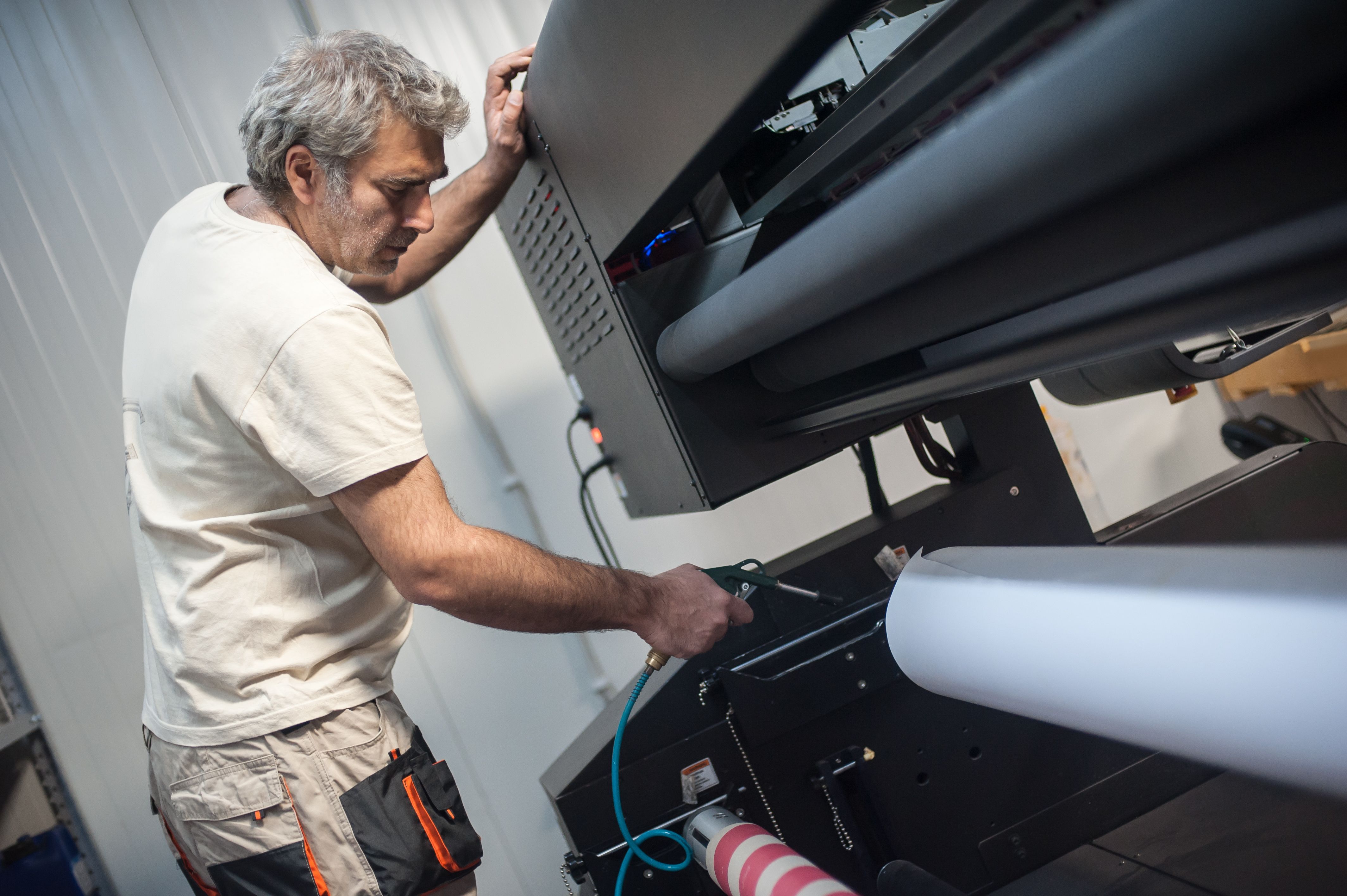 L’opérateur technicien travaille sur une grande machine de traçeuse d’imprimante industrielle haut de gamme