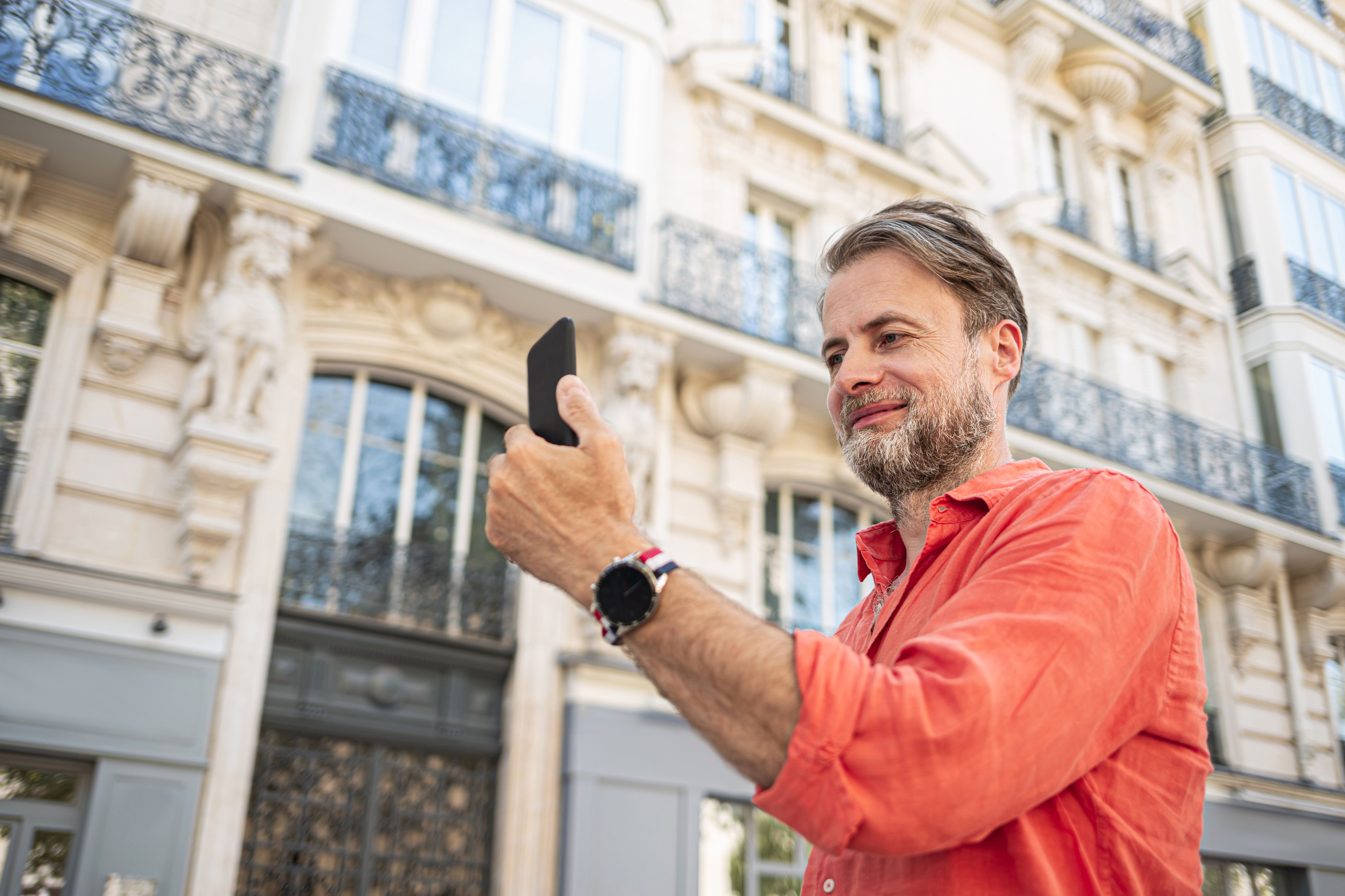 Homme caucasien (homme d’affaires) utilisant un smartphone dans l’élégante rue de Paris.