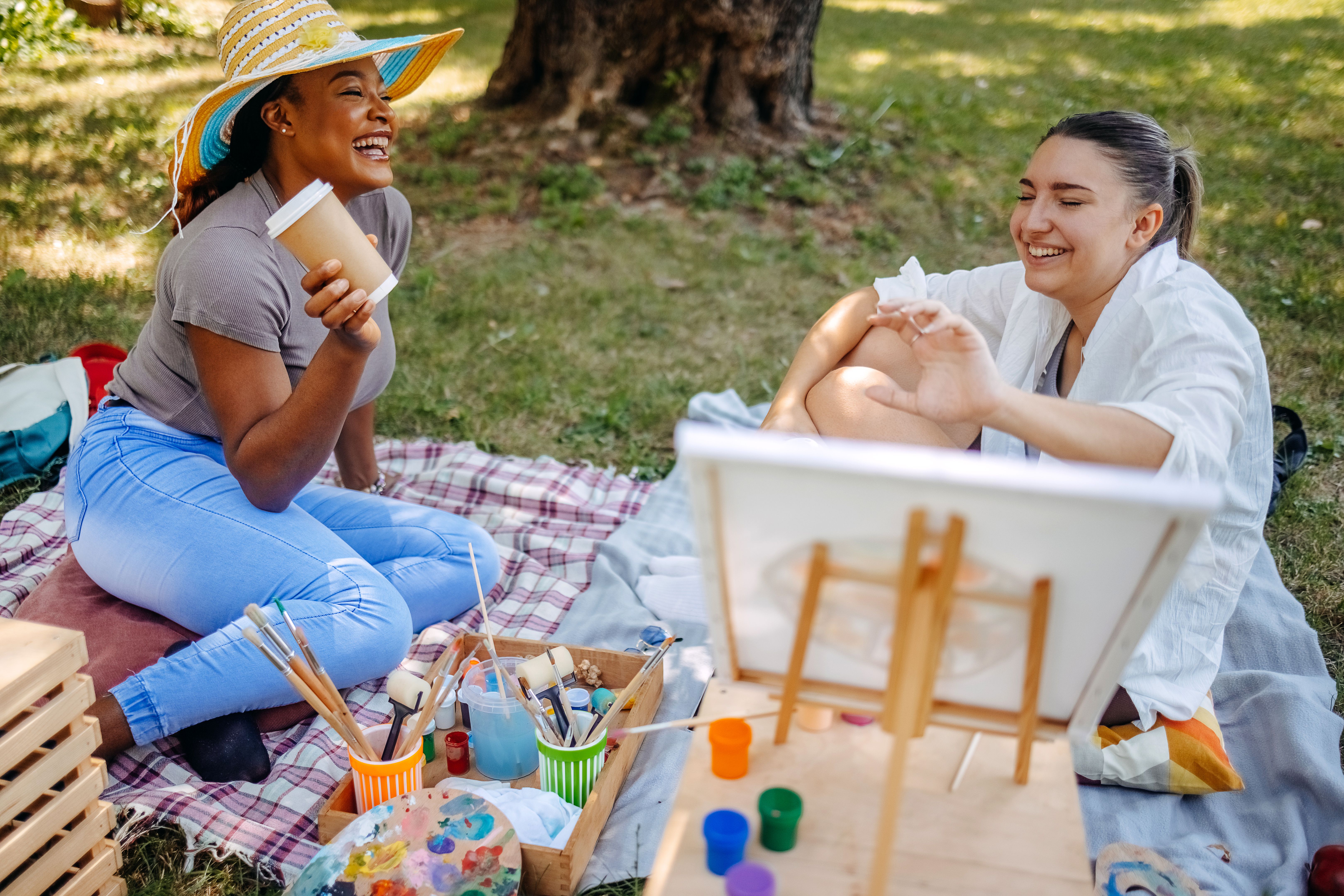 Young female artist creating painting in city park while having a coffee