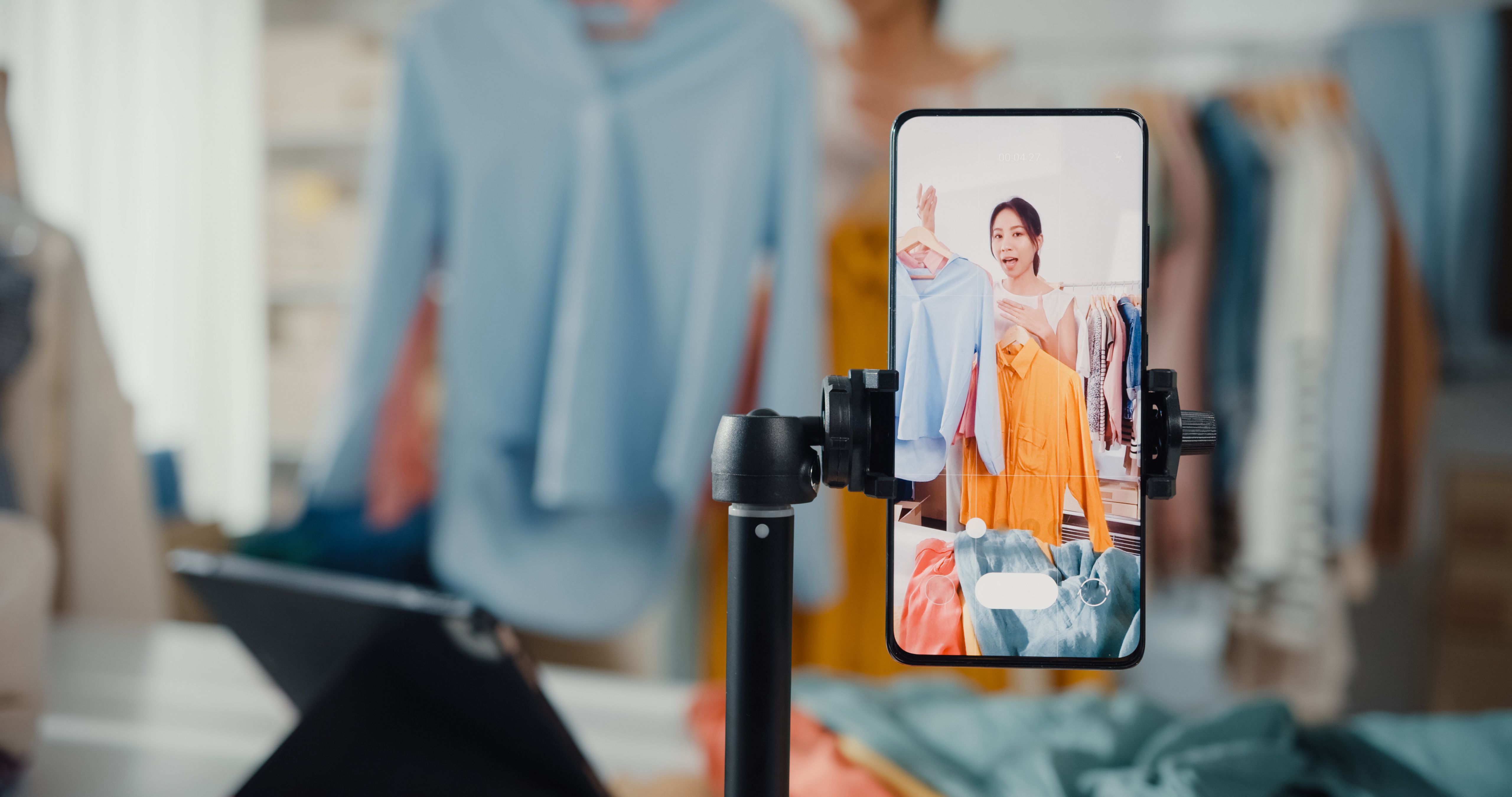 Asian businesswoman live-streamed ecommerce sell clothes at home, beautiful girl using the smartphone and tablet for recording video.