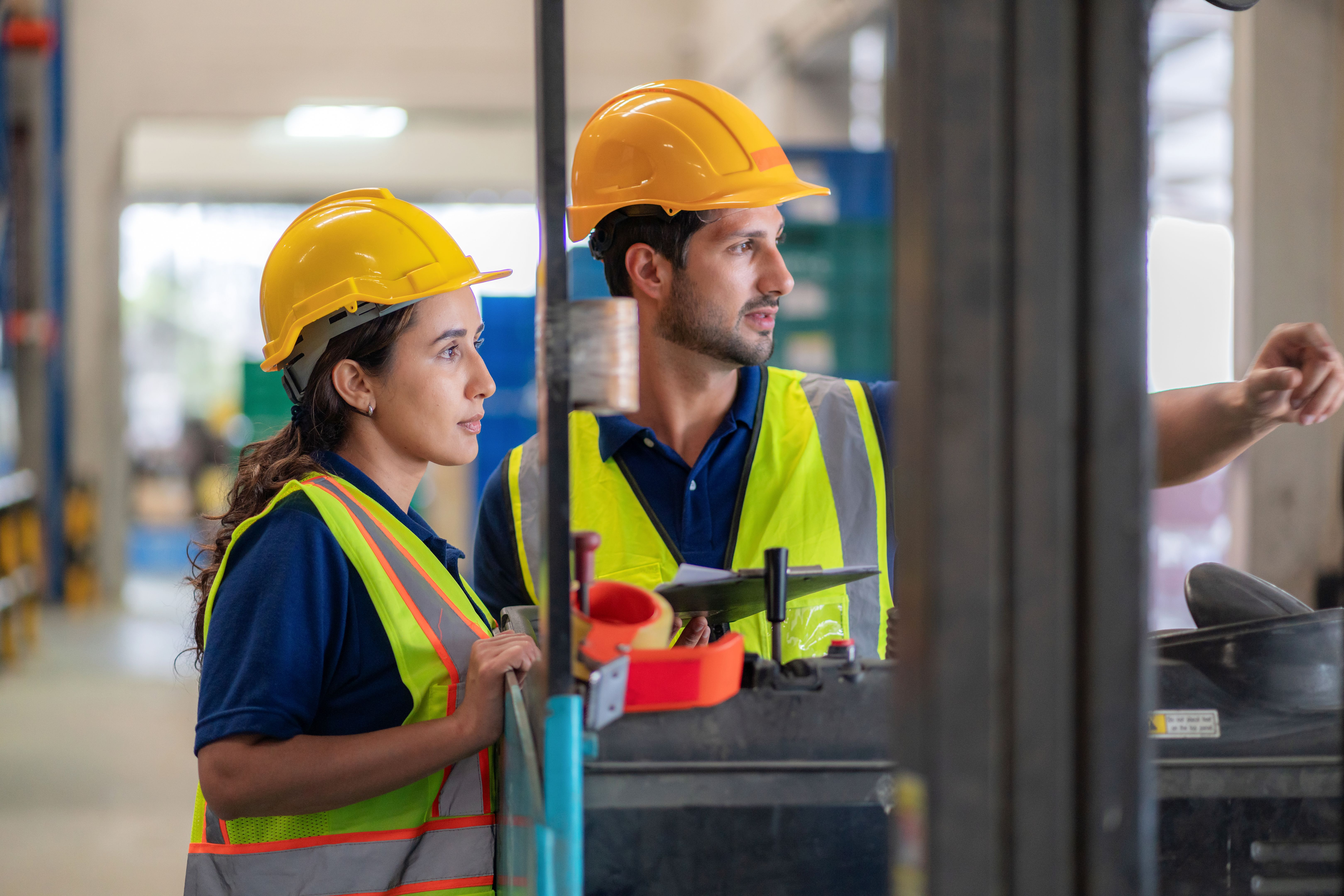 Professional warehouse team planning shipments using digital tools, ensuring efficiency and reliability in distribution. Workers stand in front of a forklift surrounded by pallets, emphasizing teamwork, logistics management, and operational success