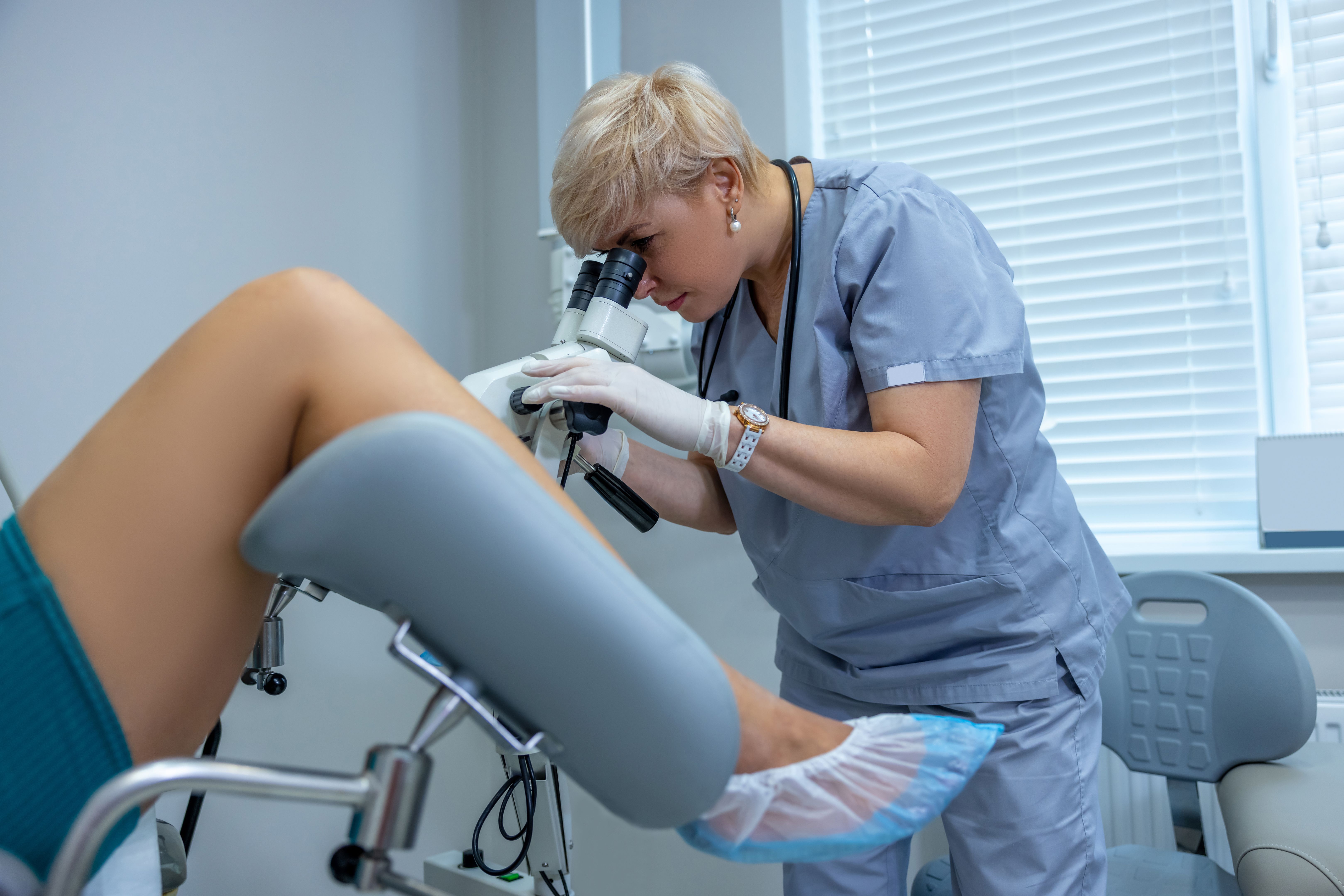 Experienced gynecologist doing colposcopy to a woman Experienced gynecologist doing colposcopy to a woman