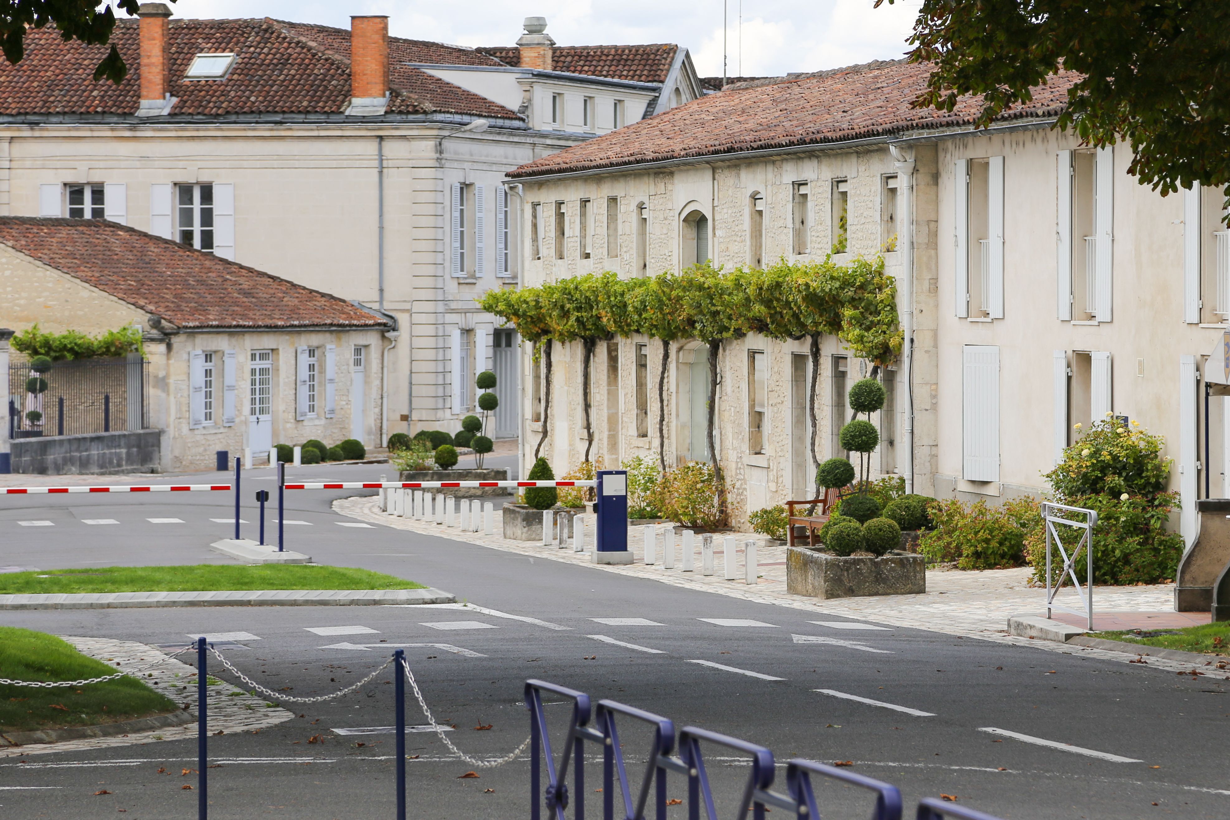 A street in Cognac France with a white building and a red and white gate