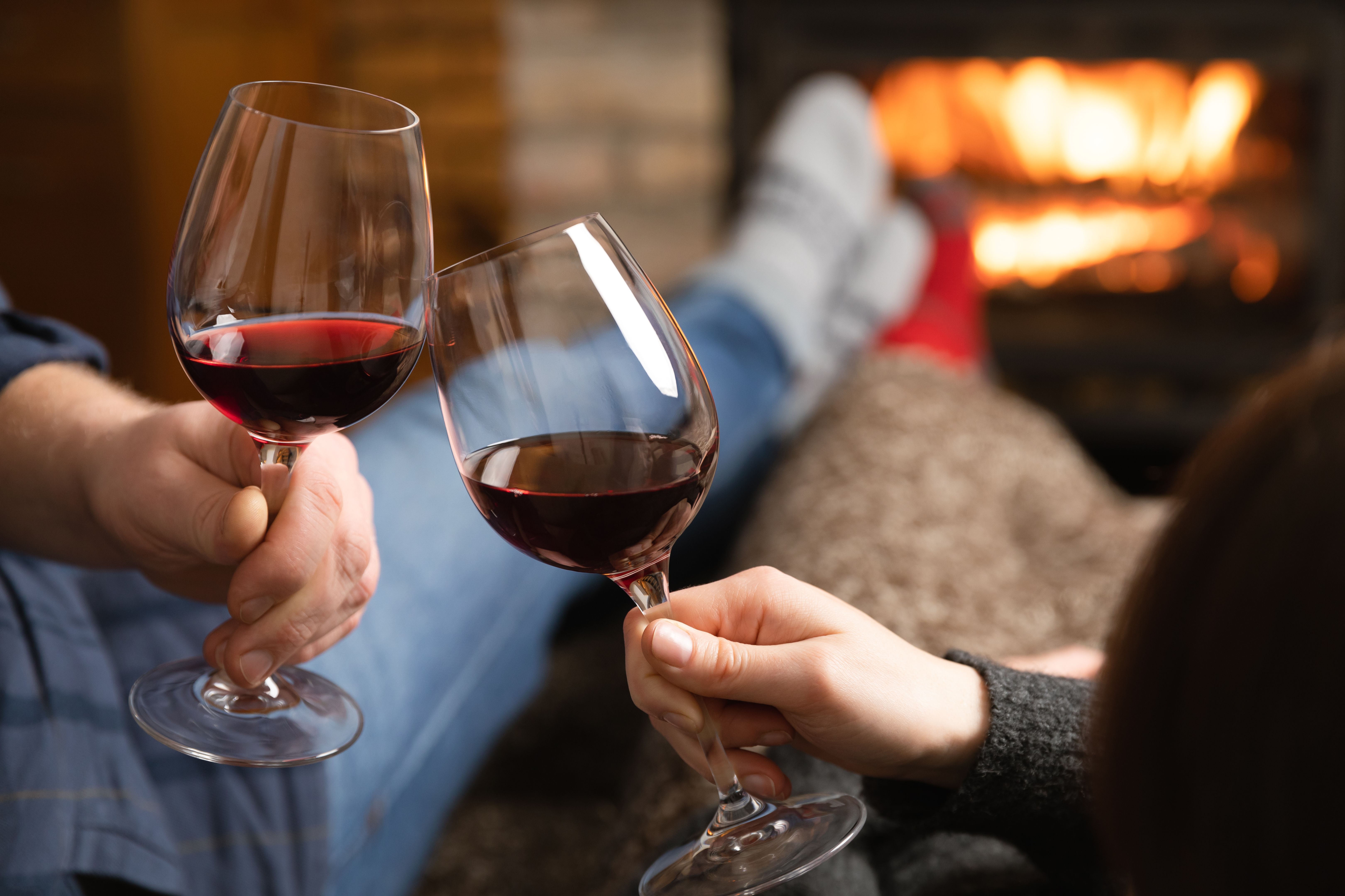 Couple in love sitting in a cozy room with fire place on a sofa with glass of wine. Family and love concept. Couple in love sitting in a cozy room with fire place on a sofa with glass of wine. Family and love concept.
