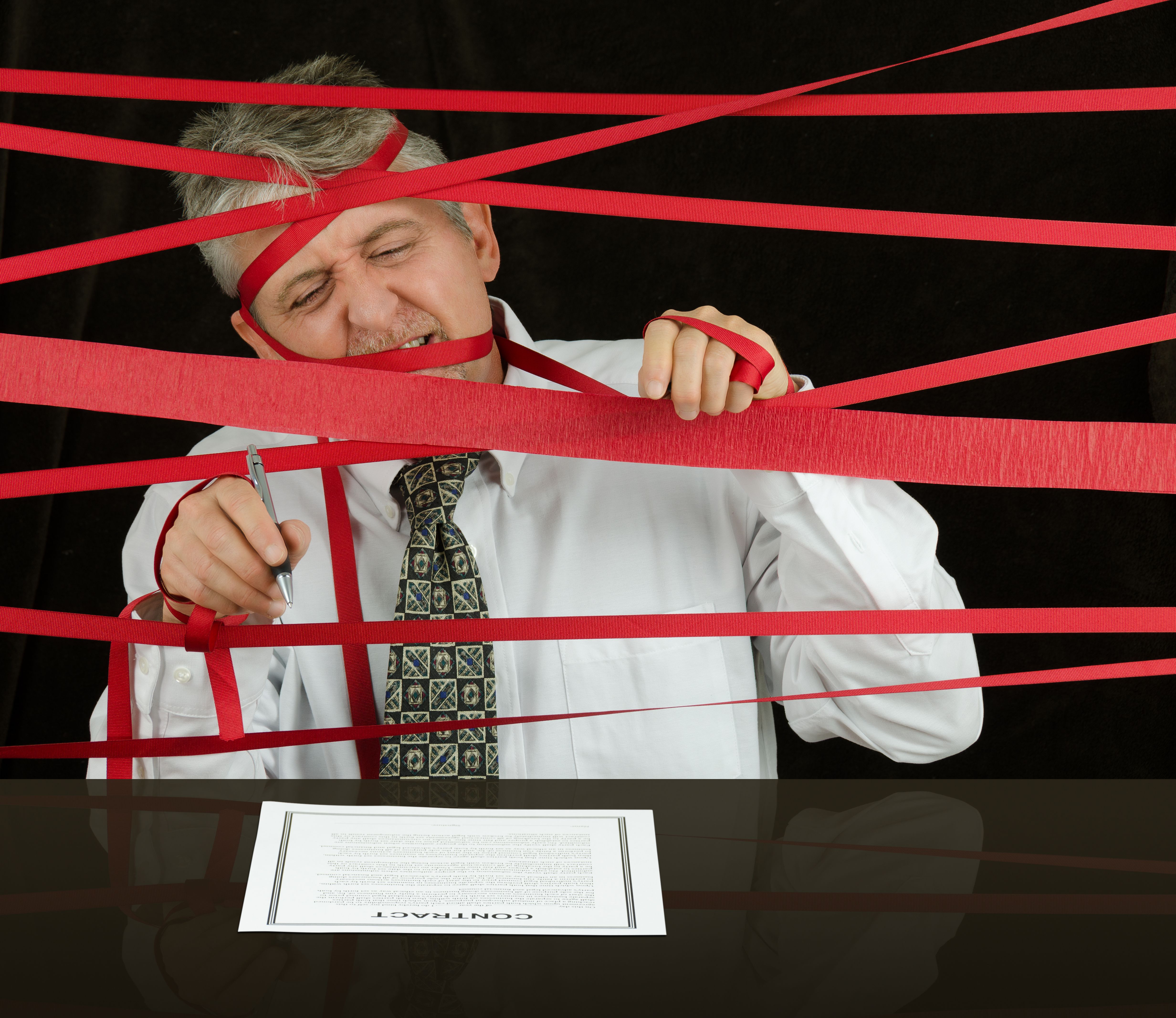 Frustrated business man caught in red tape stopping progress