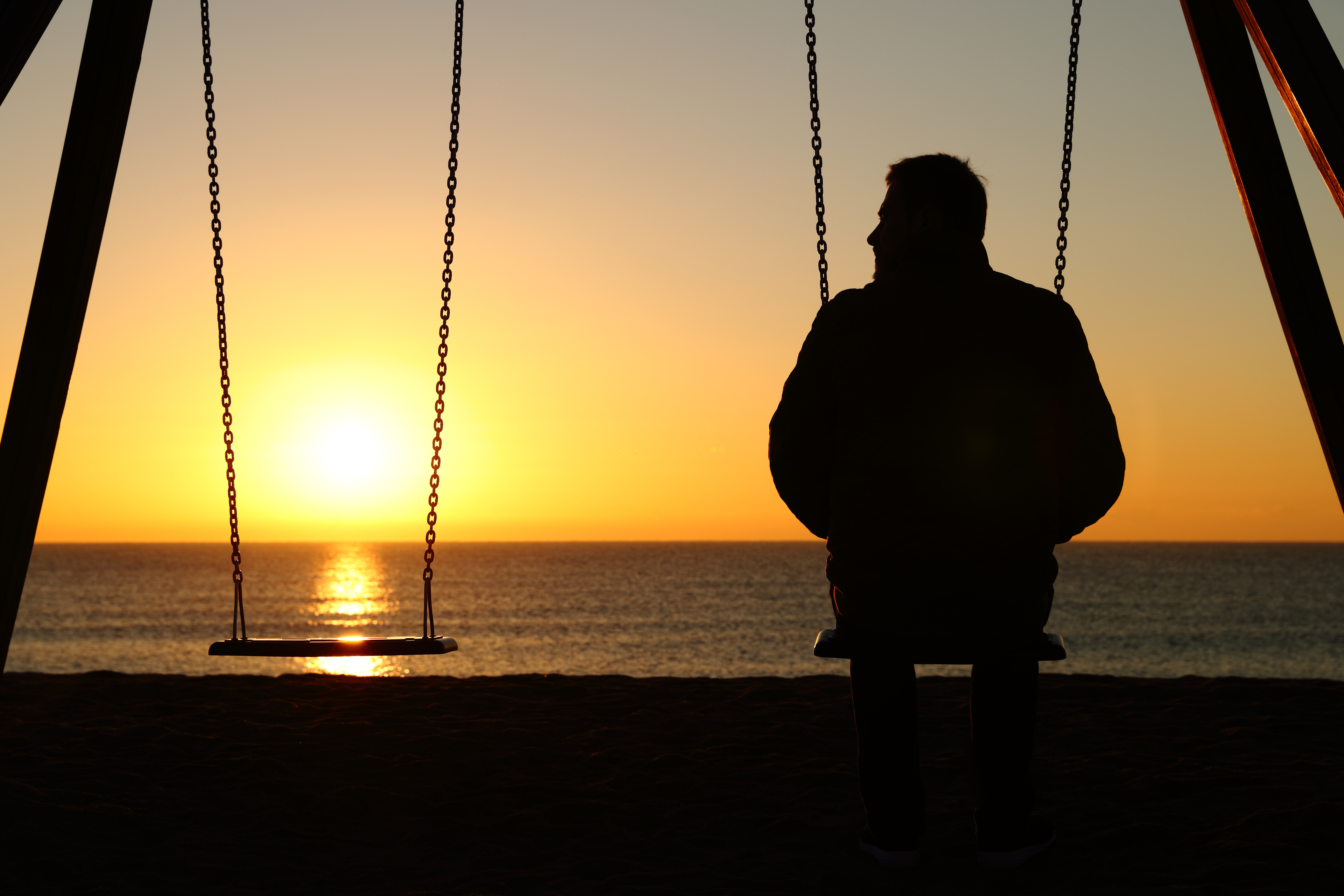 Man alone on a swing looking at empty seat Man alone on a swing looking at empty seat