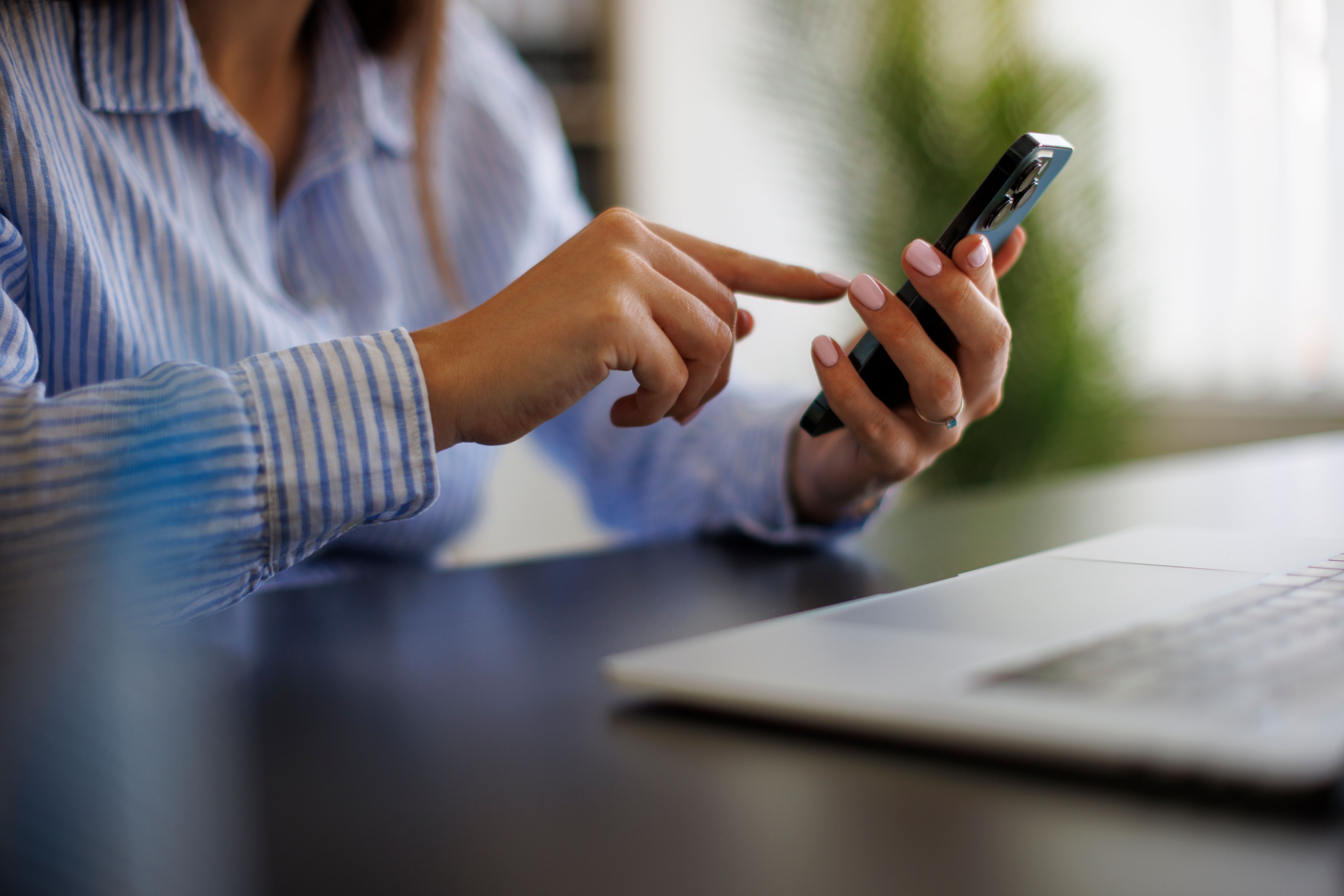 Closeup of young businesswoman using mobile phone at the office