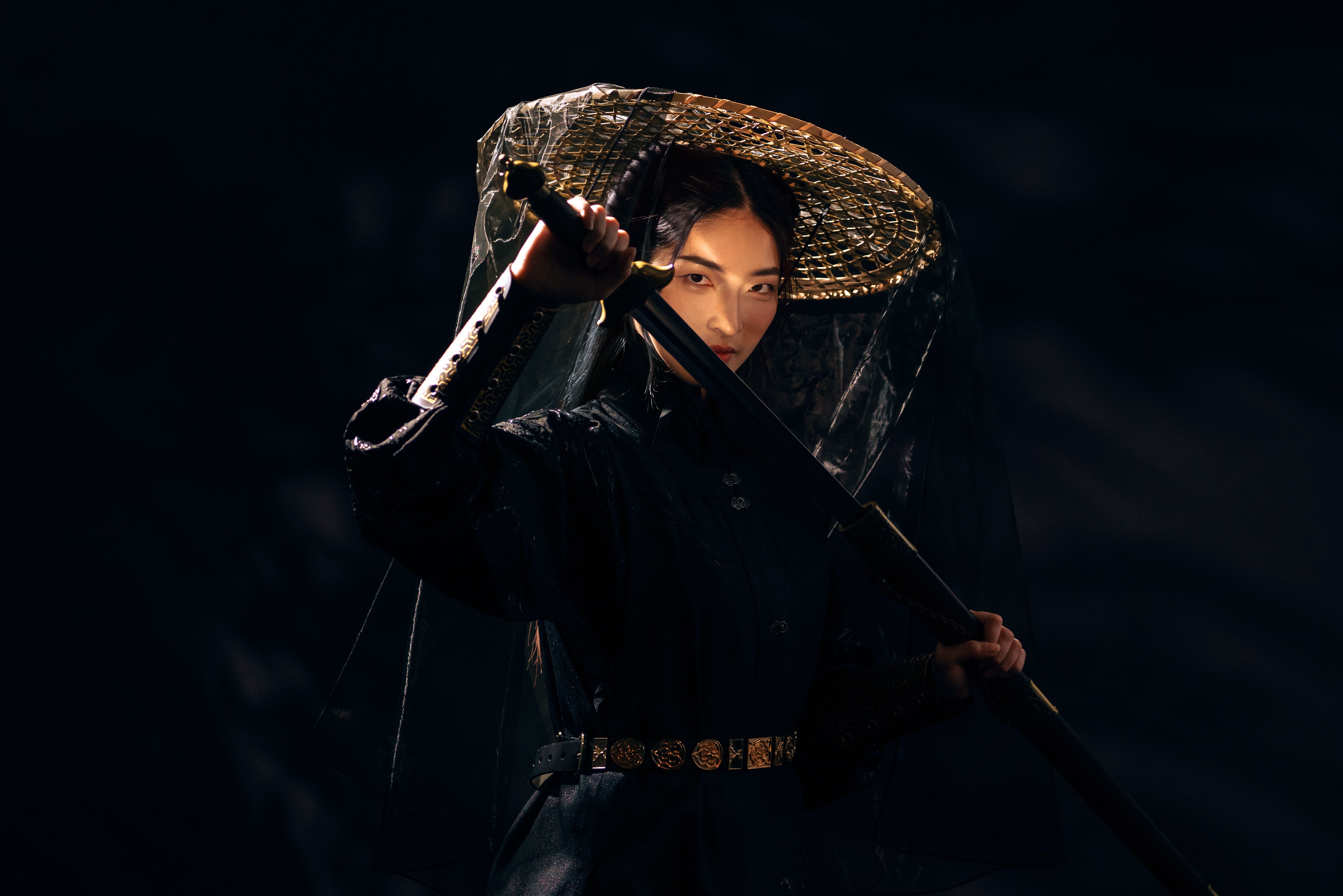 Portrait of a beautiful but deadly Asian Chinese swordswoman dressed in black period costume and a bamboo hat with veil Portrait of a beautiful but deadly Asian Chinese swordswoman dressed in black period costume and a bamboo hat with veil