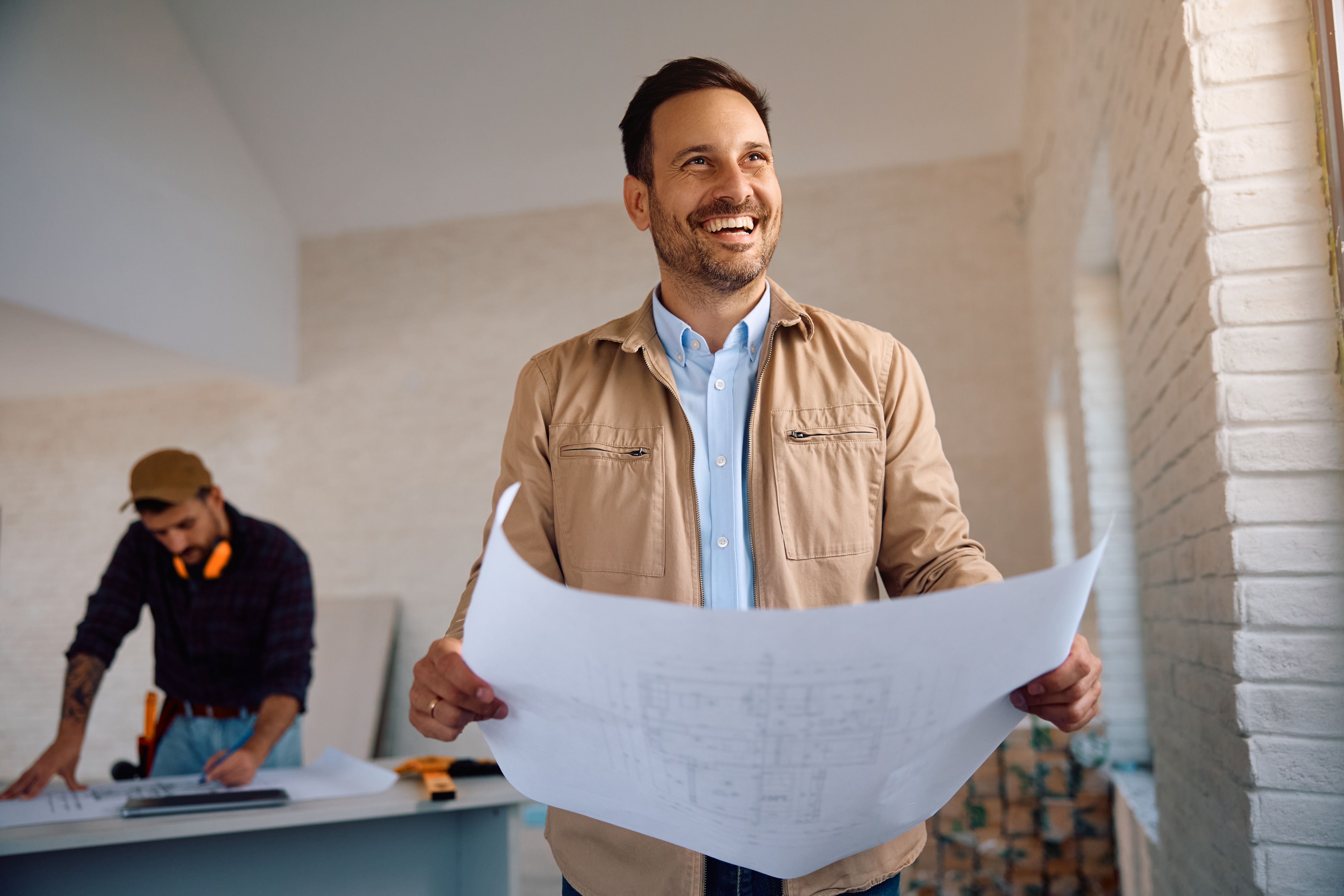 Happy man analyzing blueprints at his renovating home.