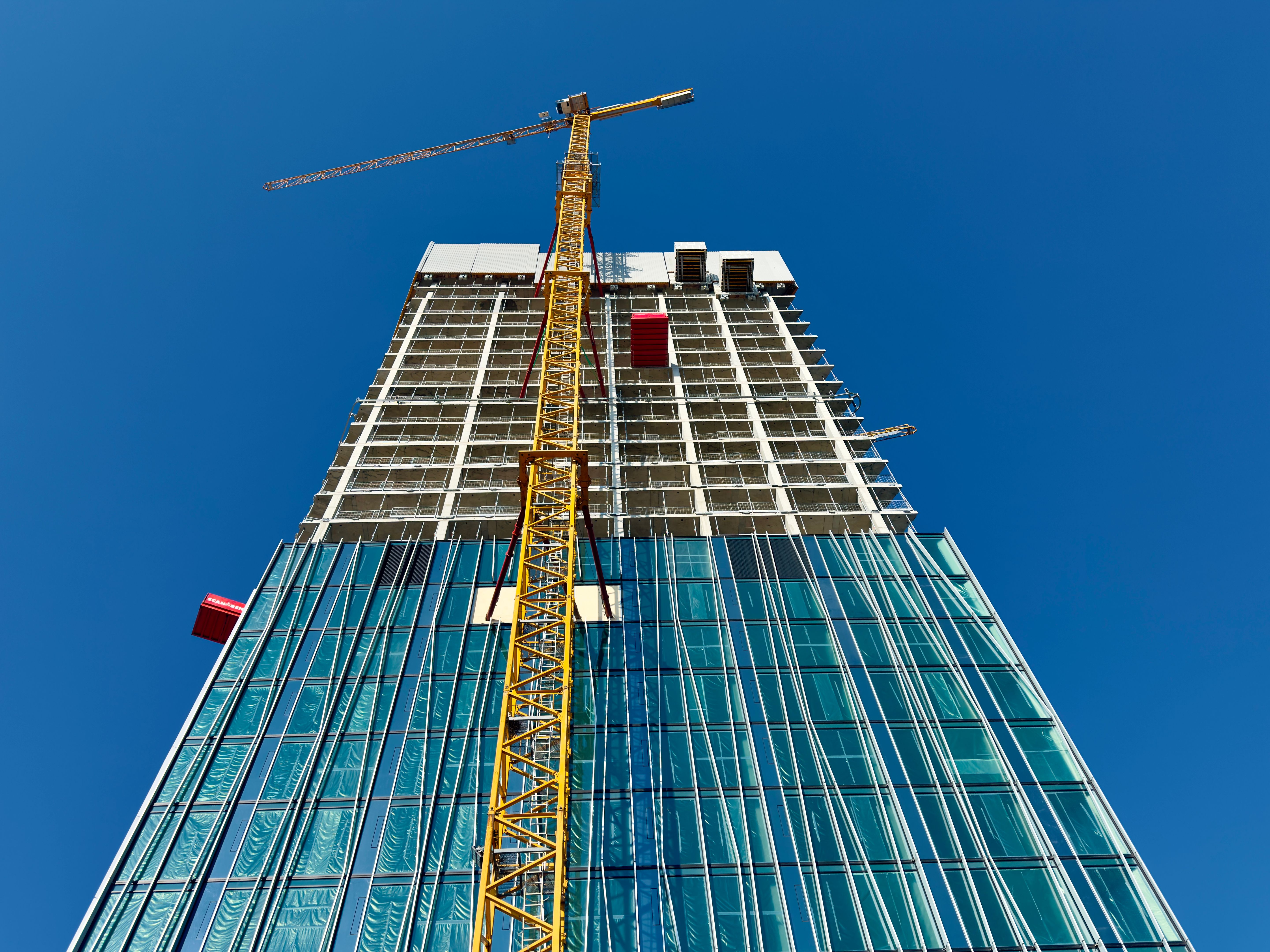 Looking up at the construction site of a high-rise building with a yellow crane