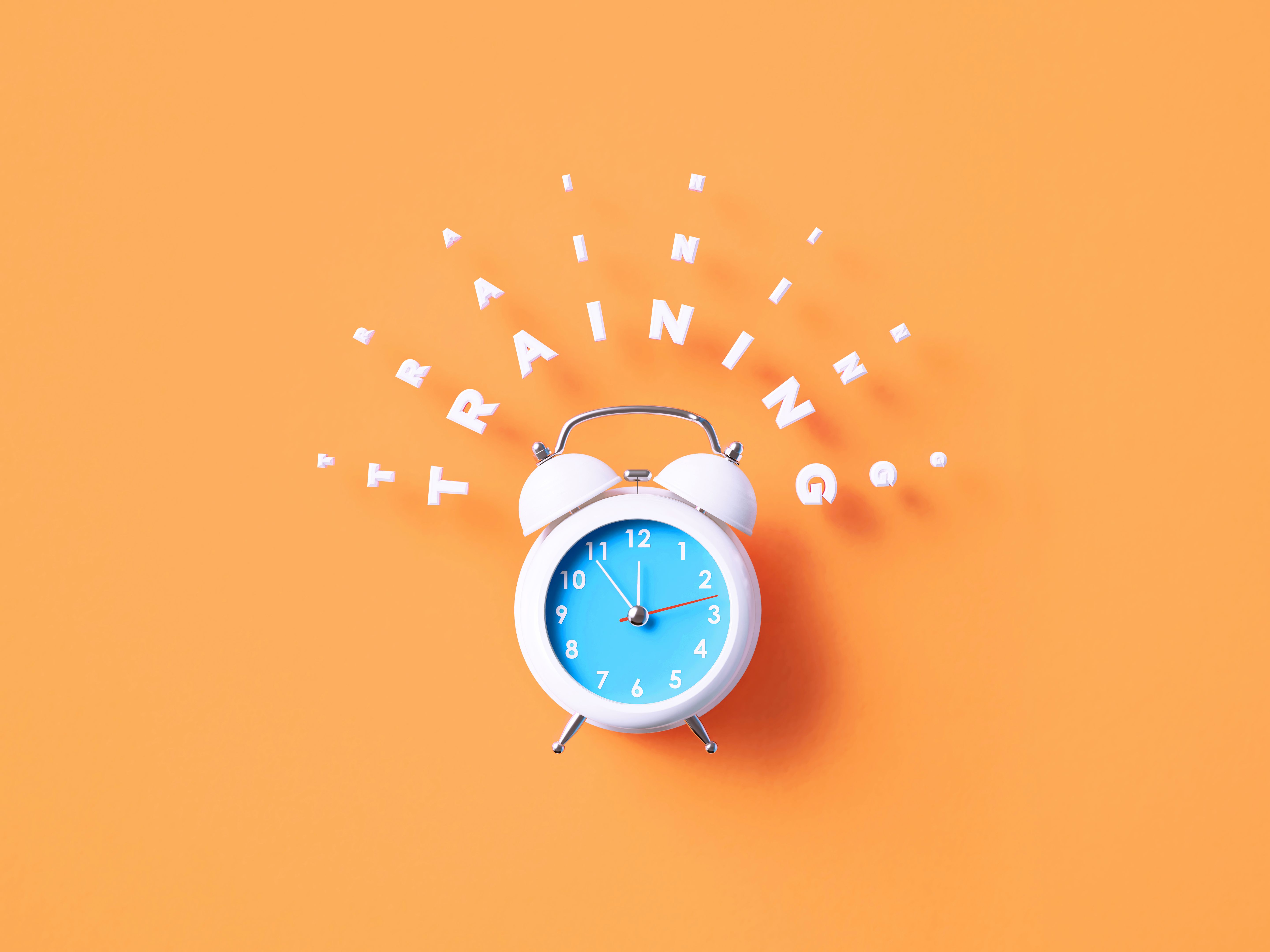 Training Message Sitting Above White Alarm Clock On Orange Background
