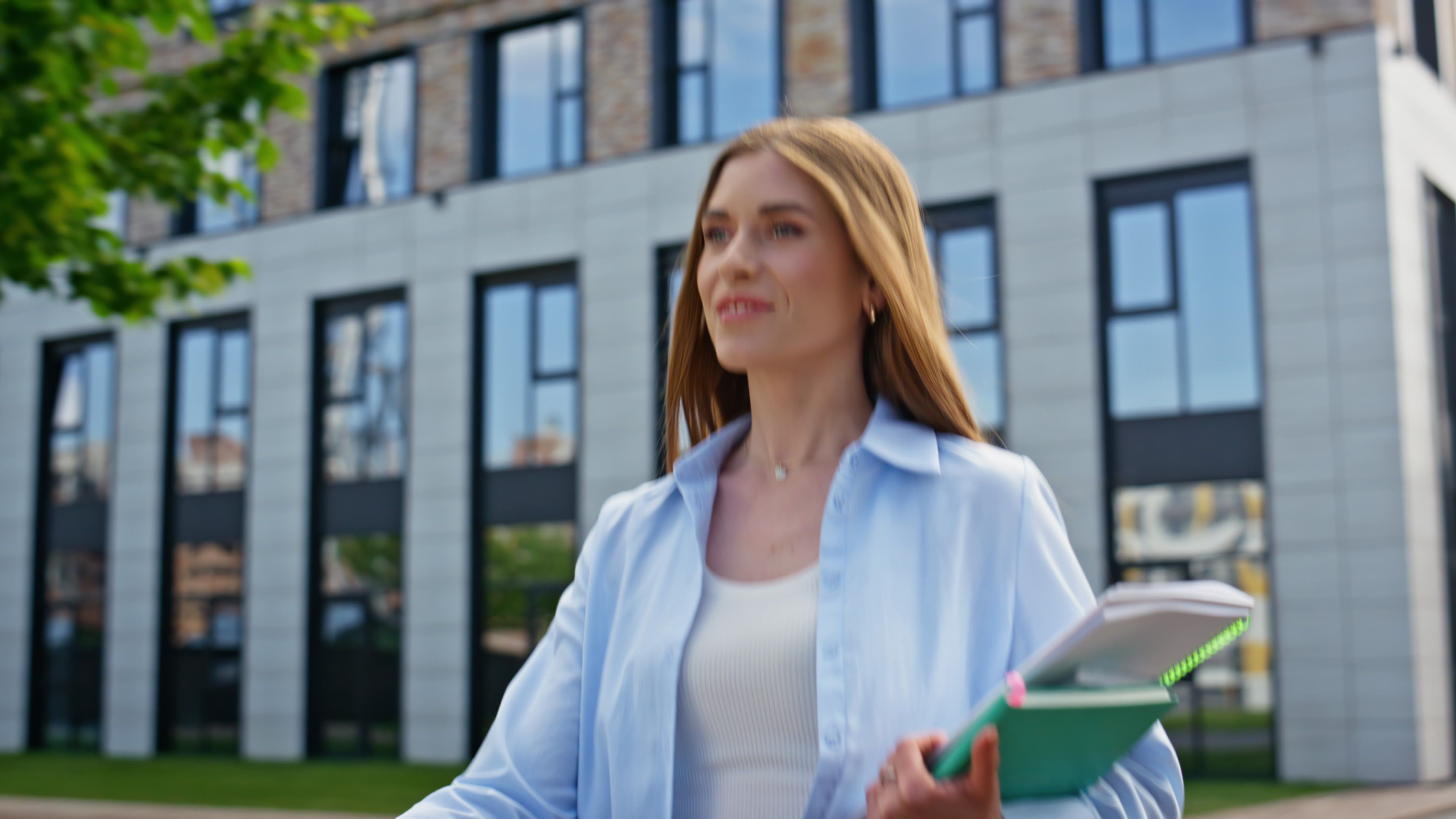 Confident woman carrying folders walking outside contemporary building closeup. Confident woman carrying folders walking outside contemporary building closeup.