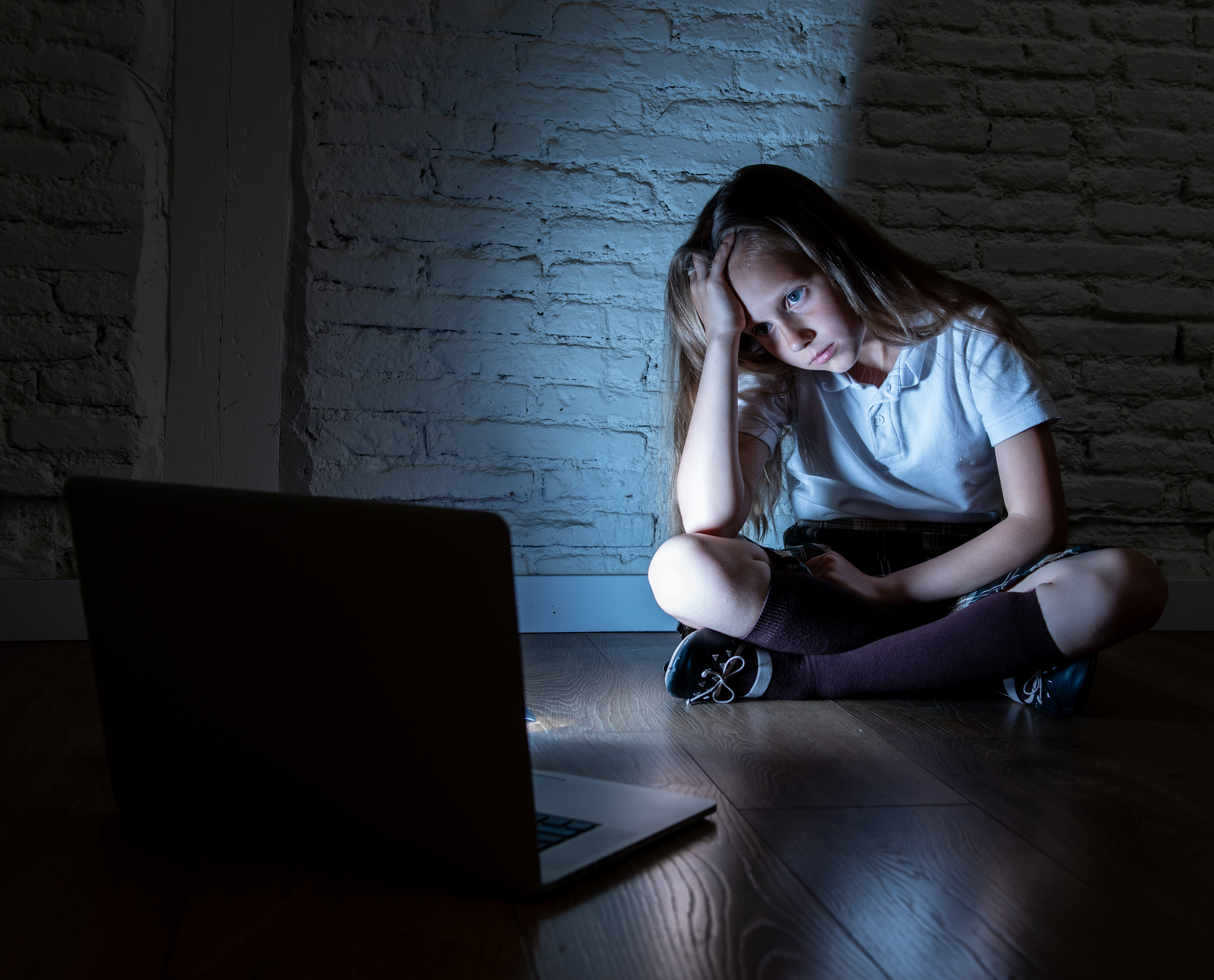 Scared sad girl bullied on line with laptop suffering cyberbullying and harassment feeling desperate and intimidated. Child victim of bullying stalker social media network