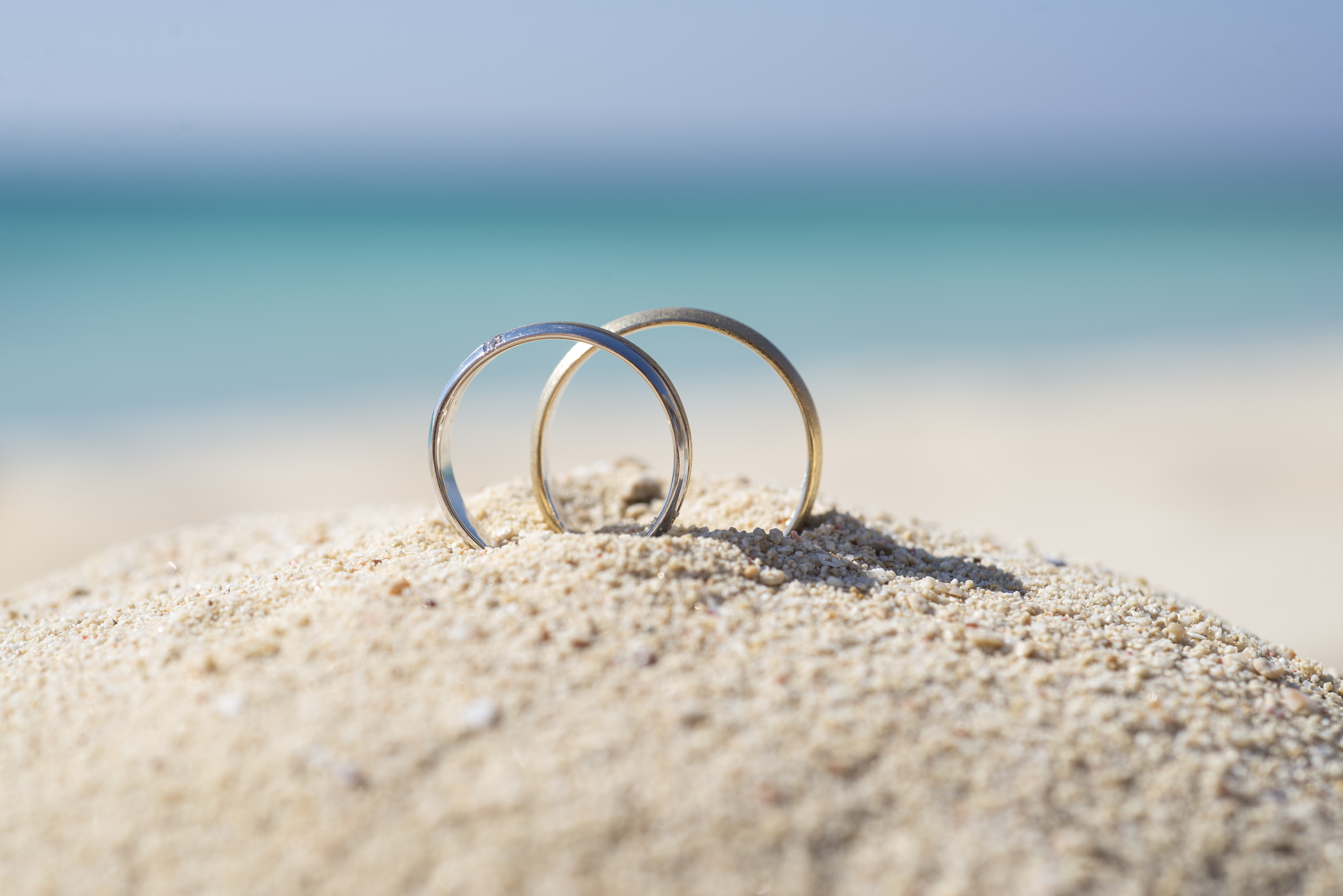 Pair wedding rings in sand on tropical beach