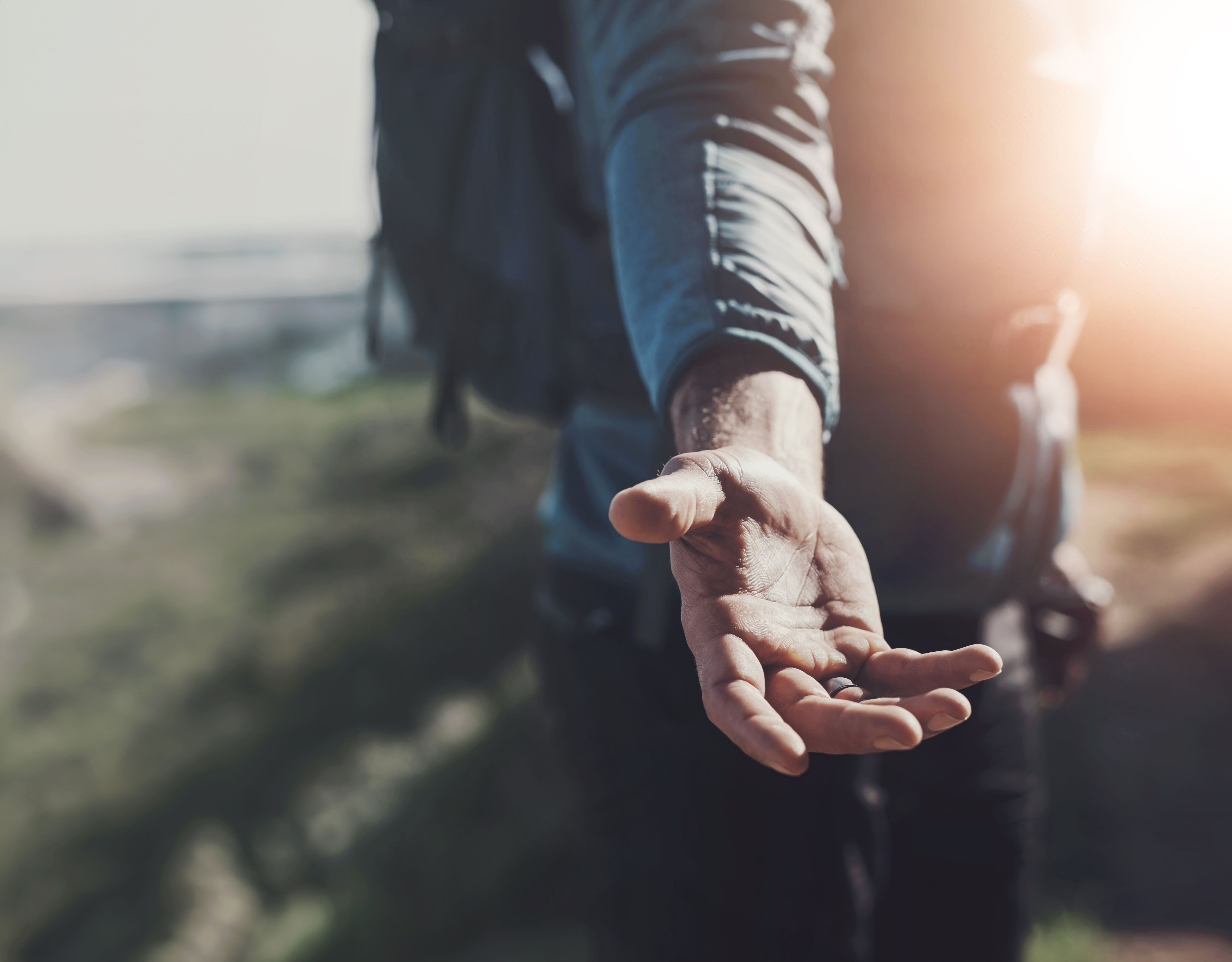 Man, hand and outdoor for help or support on hiking for adventure, fitness and explore. Person, workout and journey with trust, care and friendly with backpack as hiker for workout and exercise