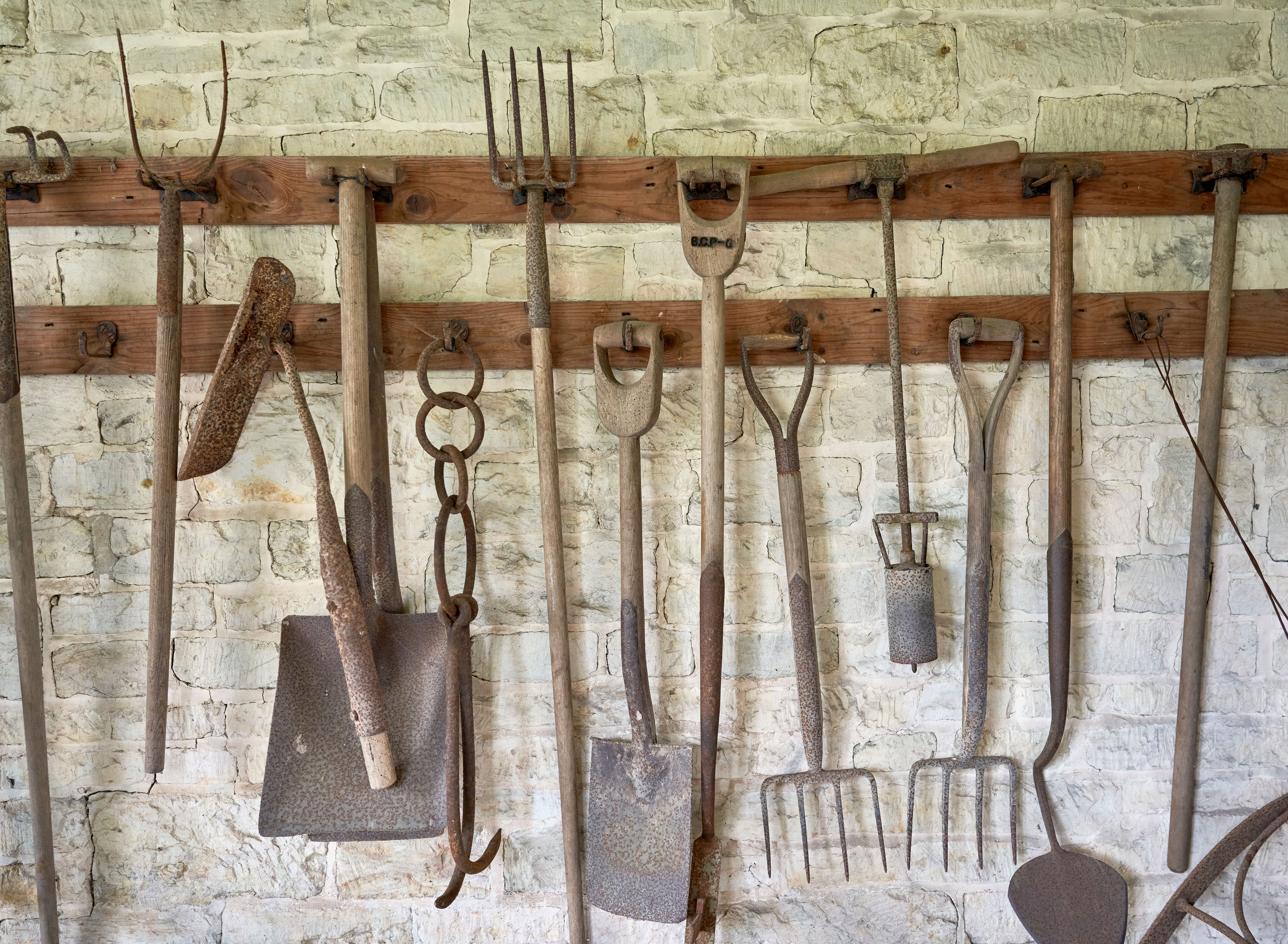 Vintage garden tools hanging on a whitewashed wall