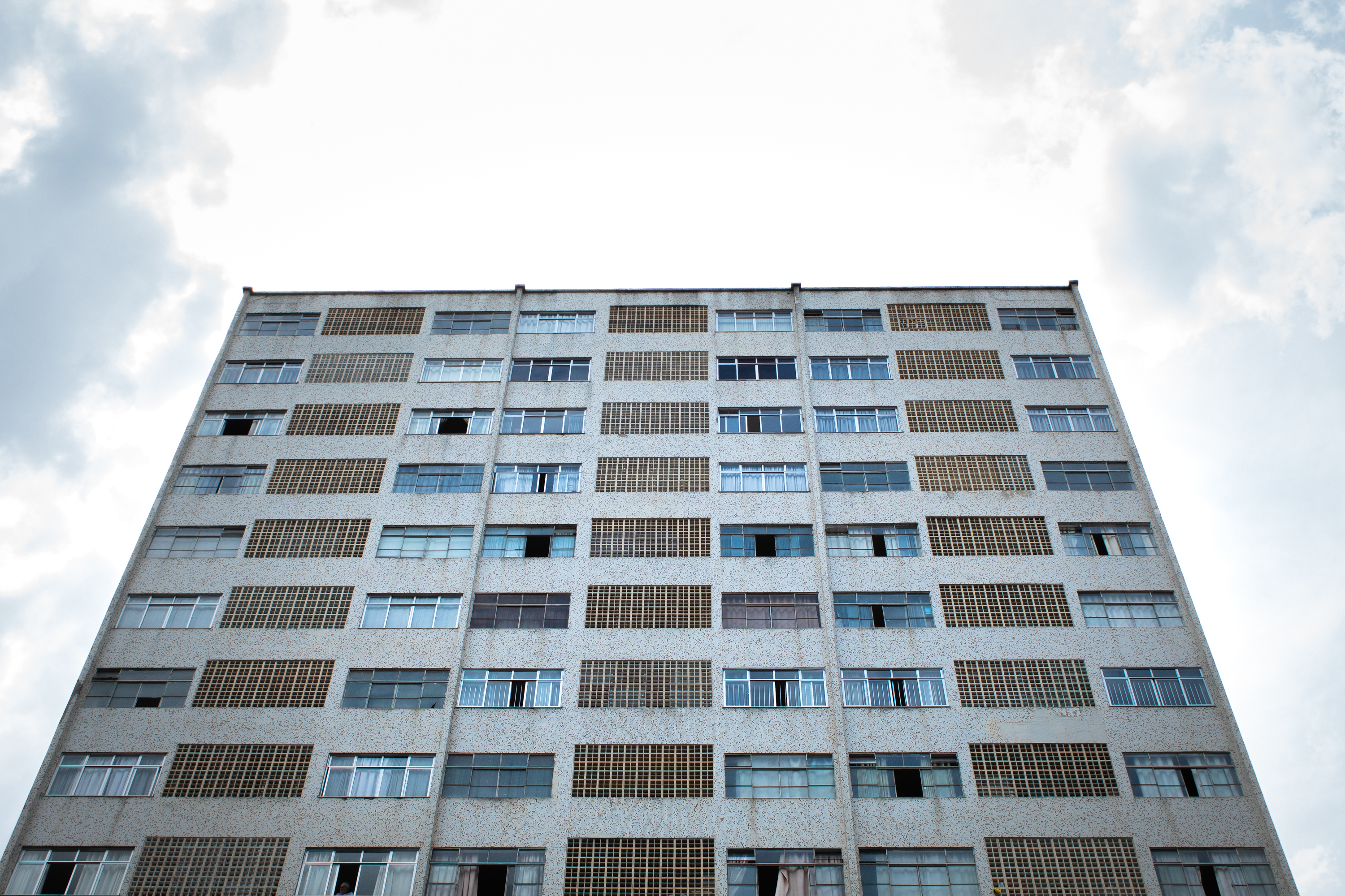 Modern grey building in the middle of the city with a cloudy day and trees under Dark Image/ Dark image of a beautiful and modern building on the city