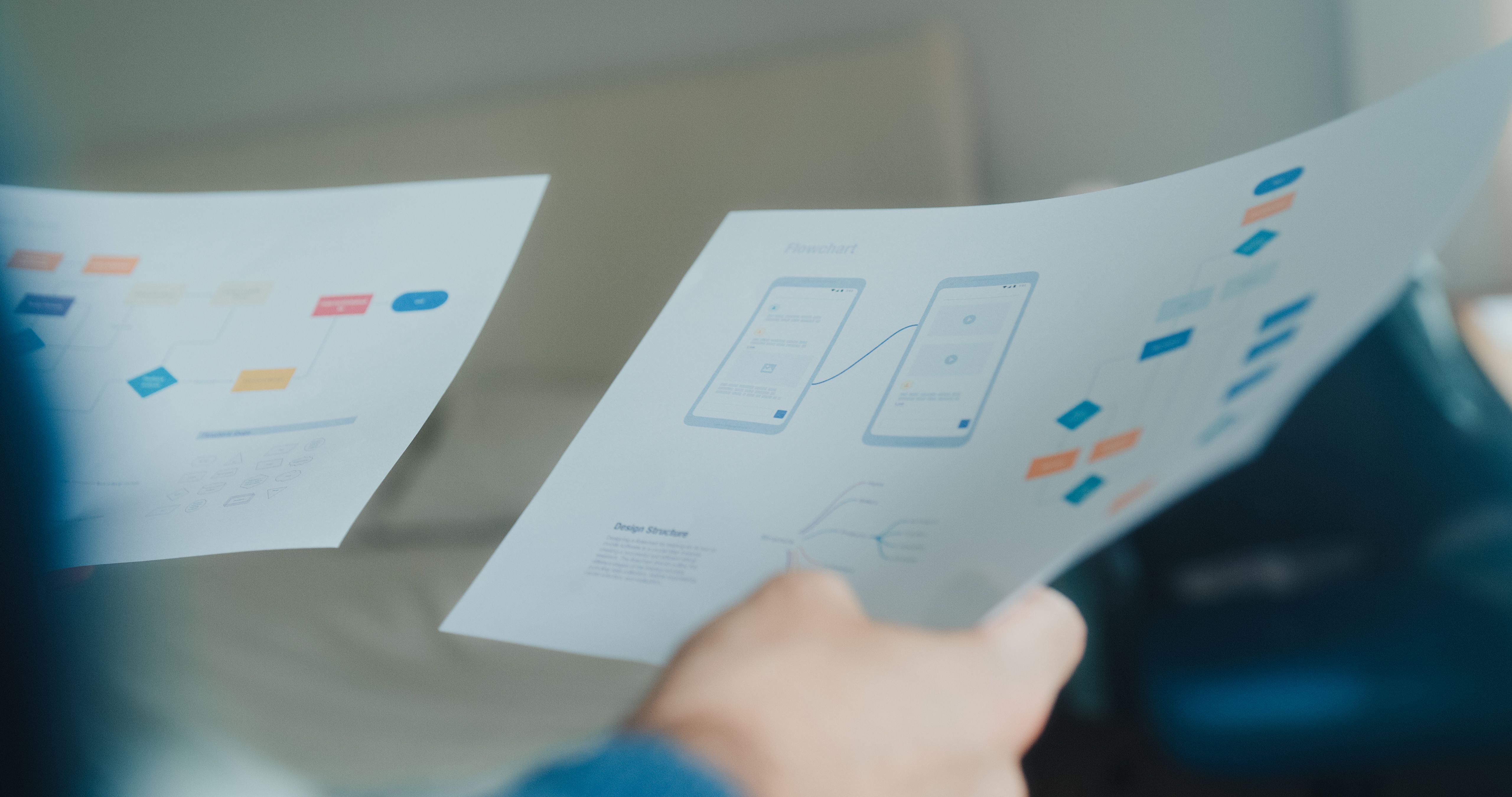 Young gay IT specialist software developer working examining UX UI flowcharts and design wireframes for a mobile app, design on laptop in bedroom at home. Artificial intelligence.