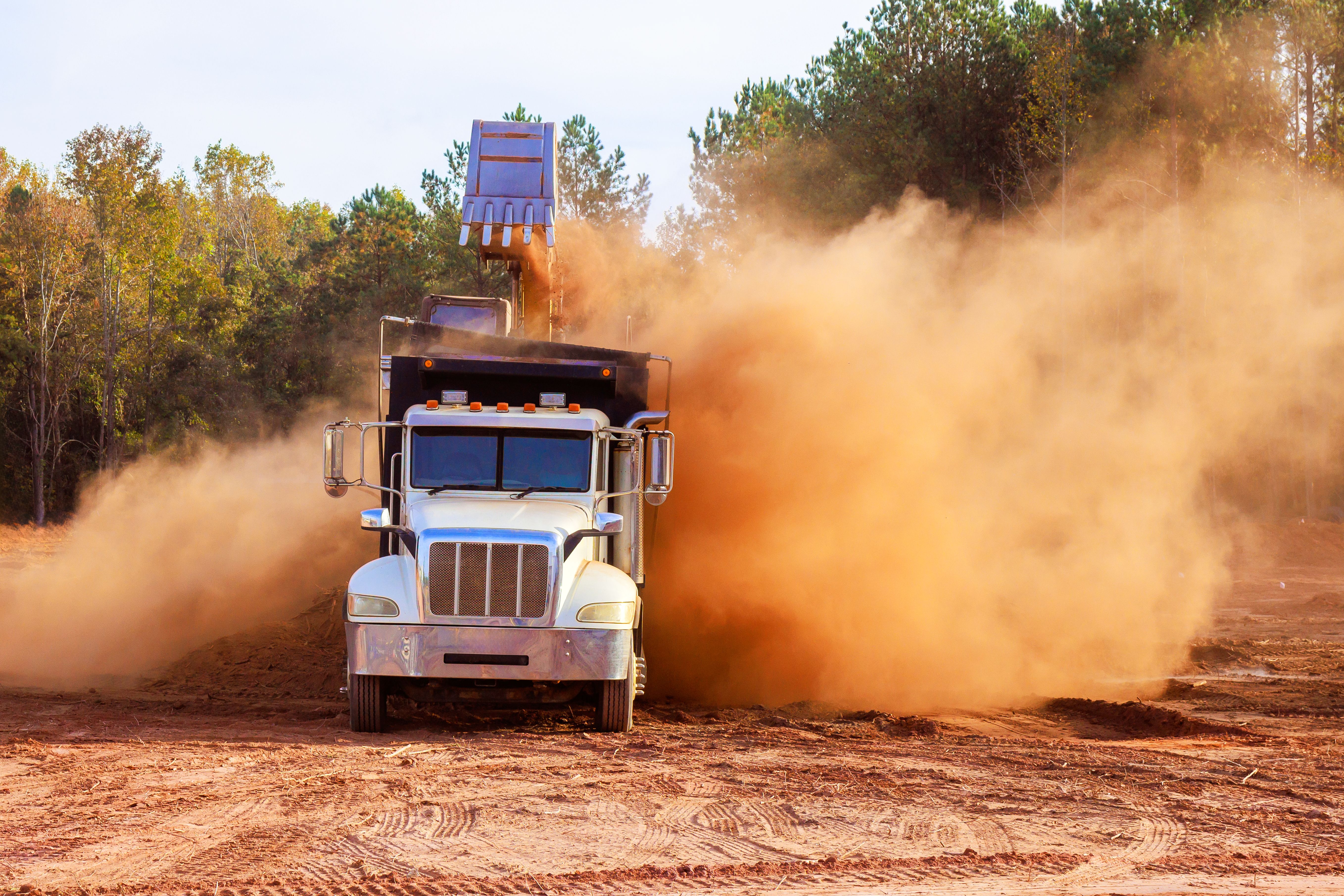 Construction truck at work creating dust in construction area during land removal