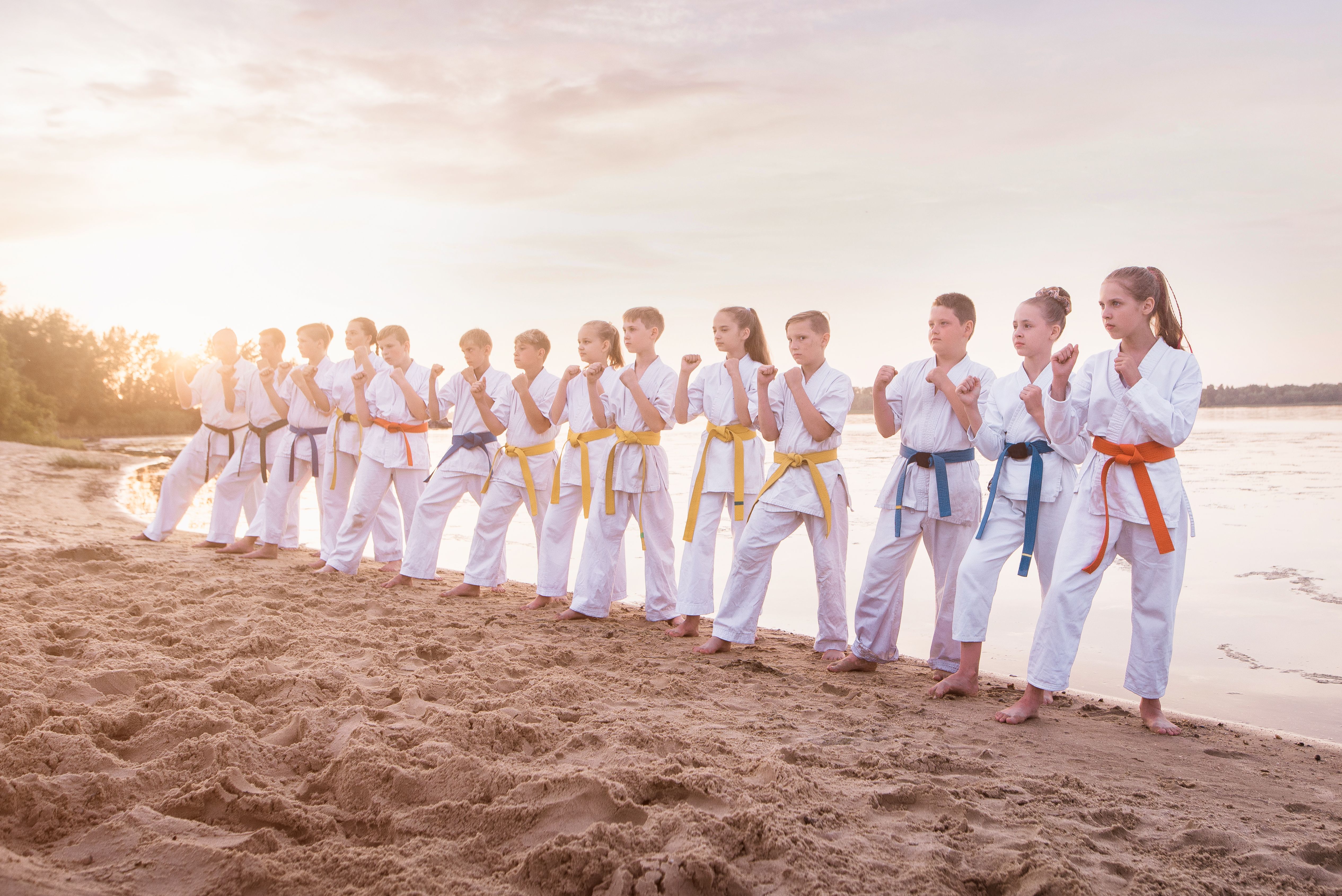 group of kids training karate martial arts on sunset beach