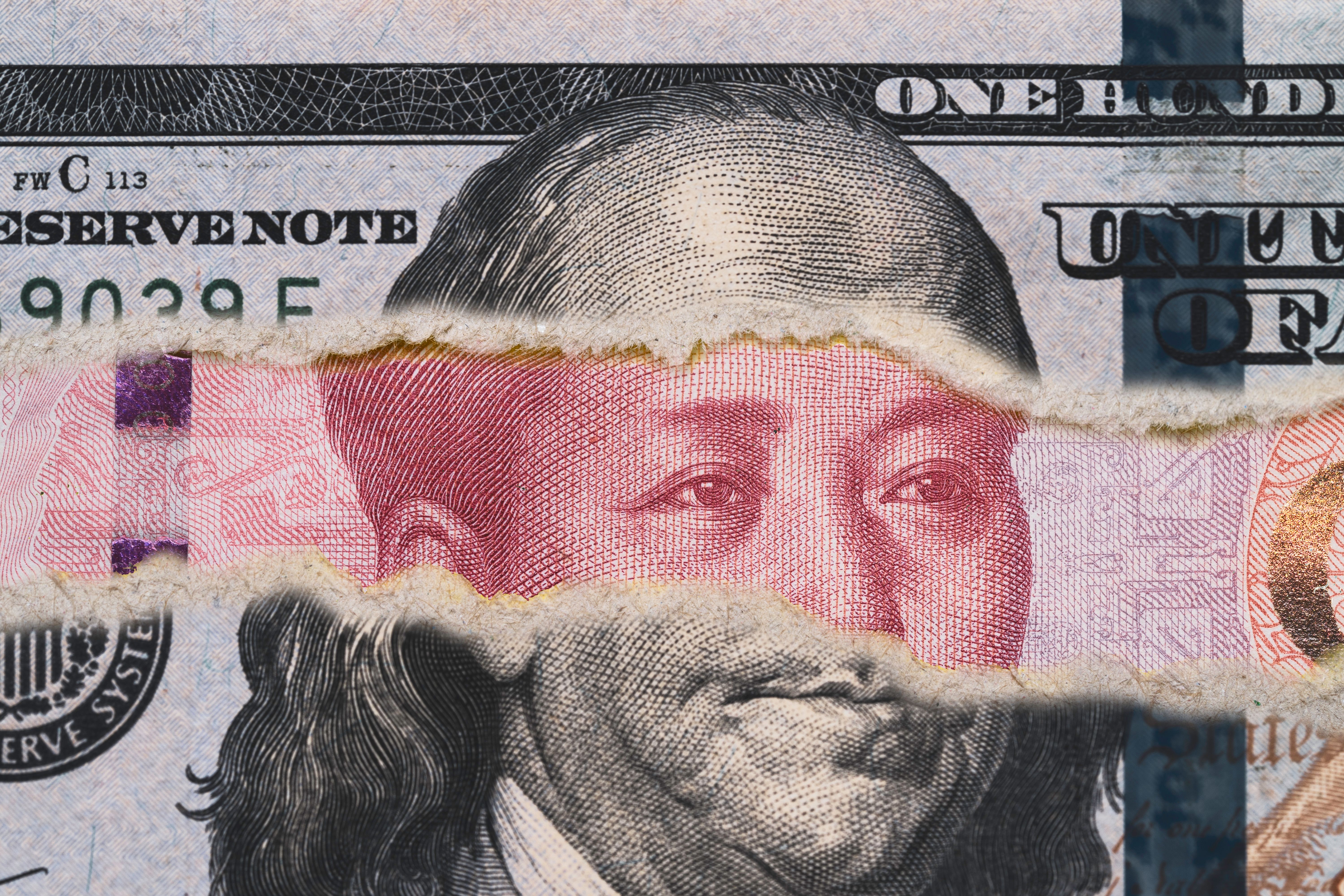 Benjamin Franklin on USD dollar banknote tear with Mao Tse Tung on Yuan banknote for competitive countries both business and military concept.