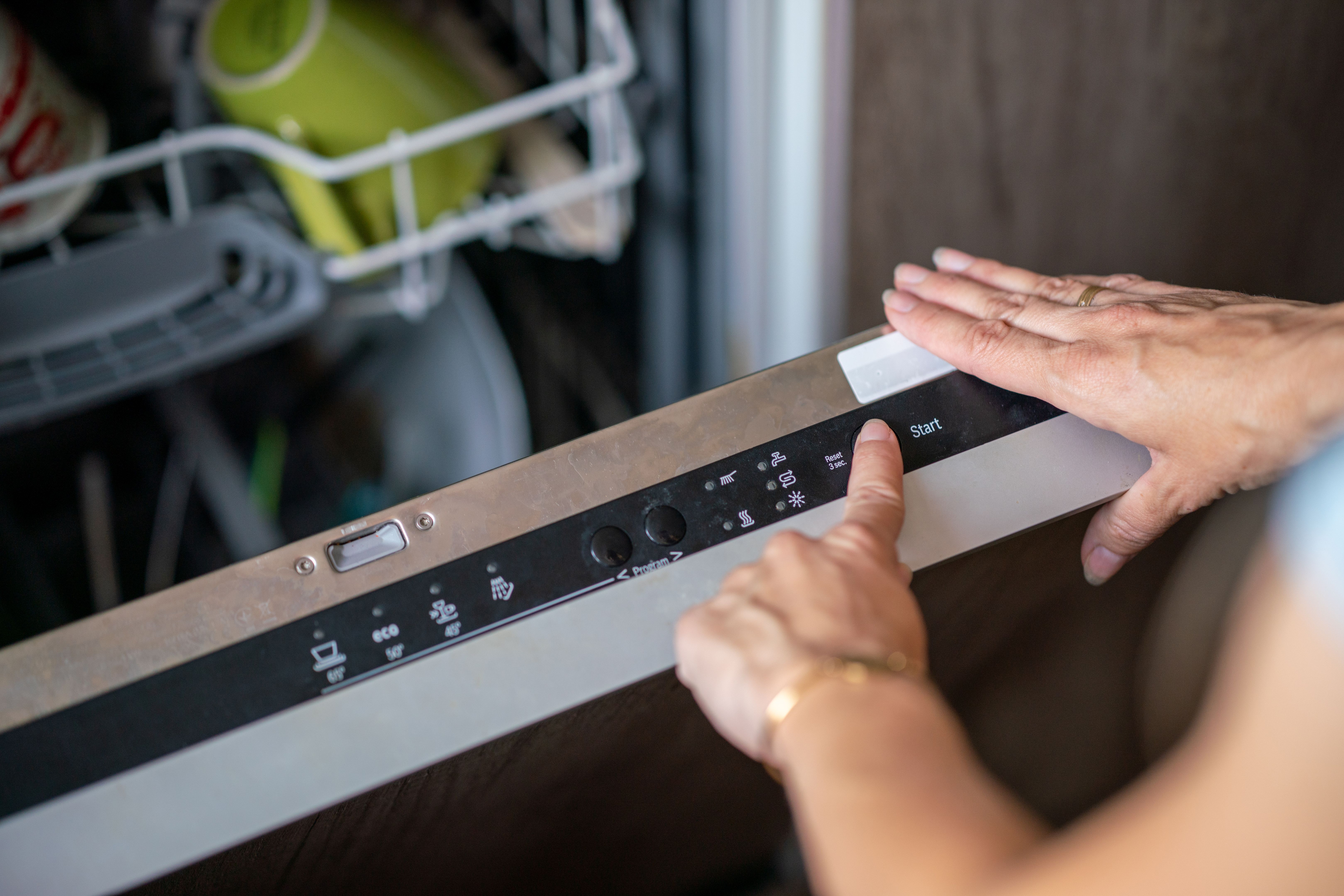 Close-up of woman setting cycle on dishwasher