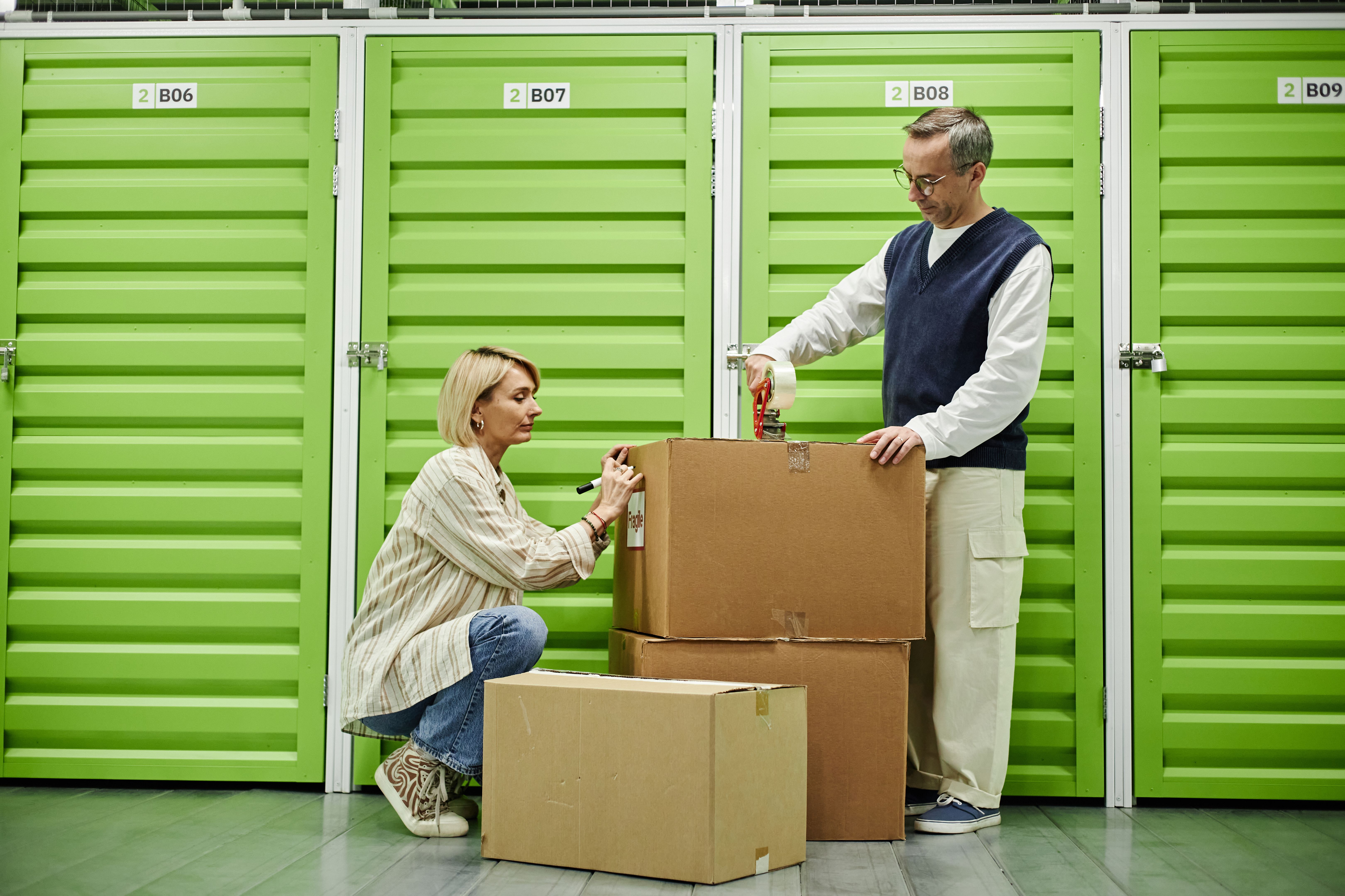 Hombre y mujer caucásicos de mediana edad empacando cajas de cartón en instalaciones de almacenamiento