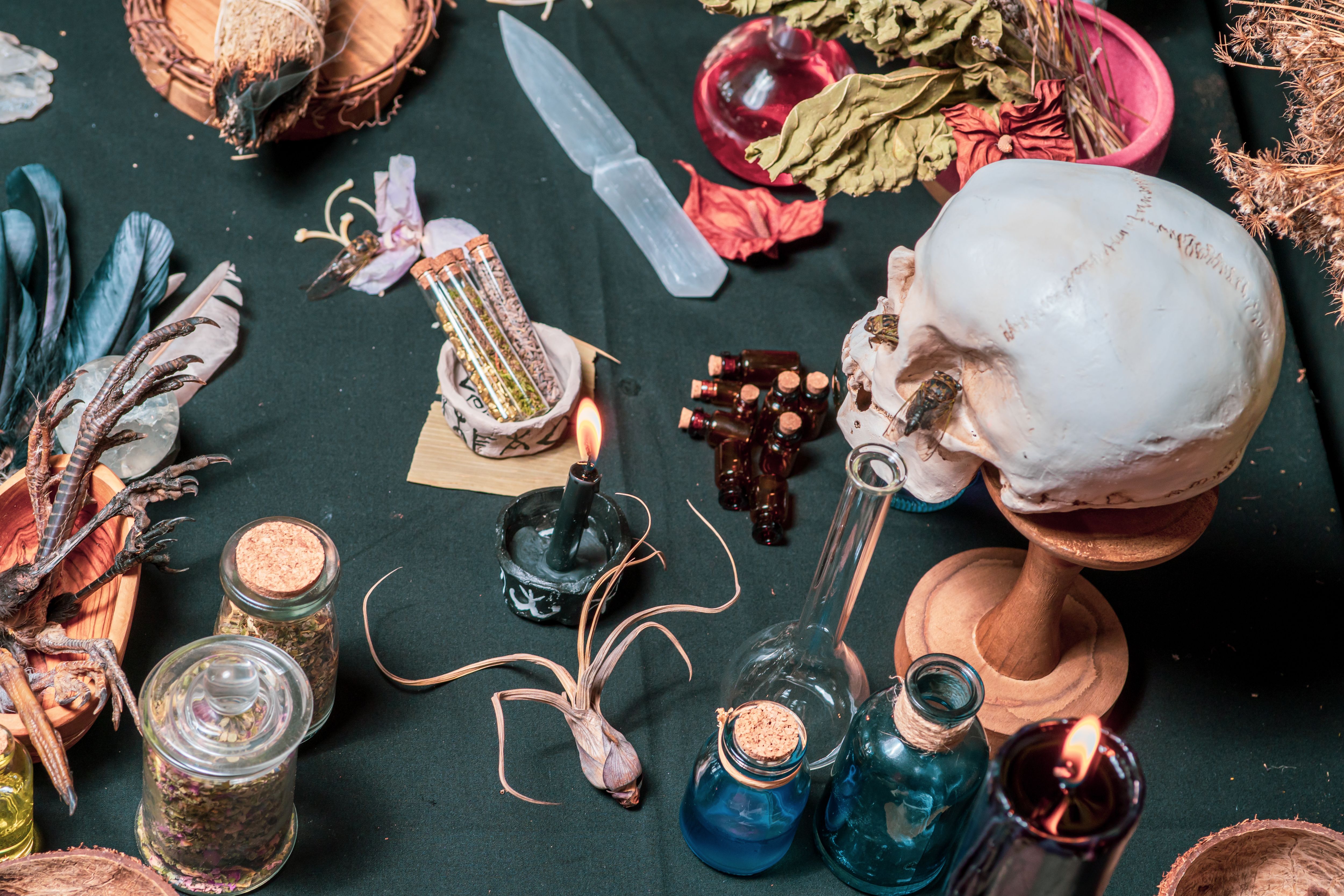 Witchcraft ceremony arranged with witch religious magic symbols. Magic items and tools. Black magic candles, ritual dry weeds, animal bones and potion vials. Halloween concept. Witchcraft ceremony arranged with witch religious magic symbols. Magic items and tools. Black magic candles, ritual dry weeds, animal bones and potion vials. Halloween concept.