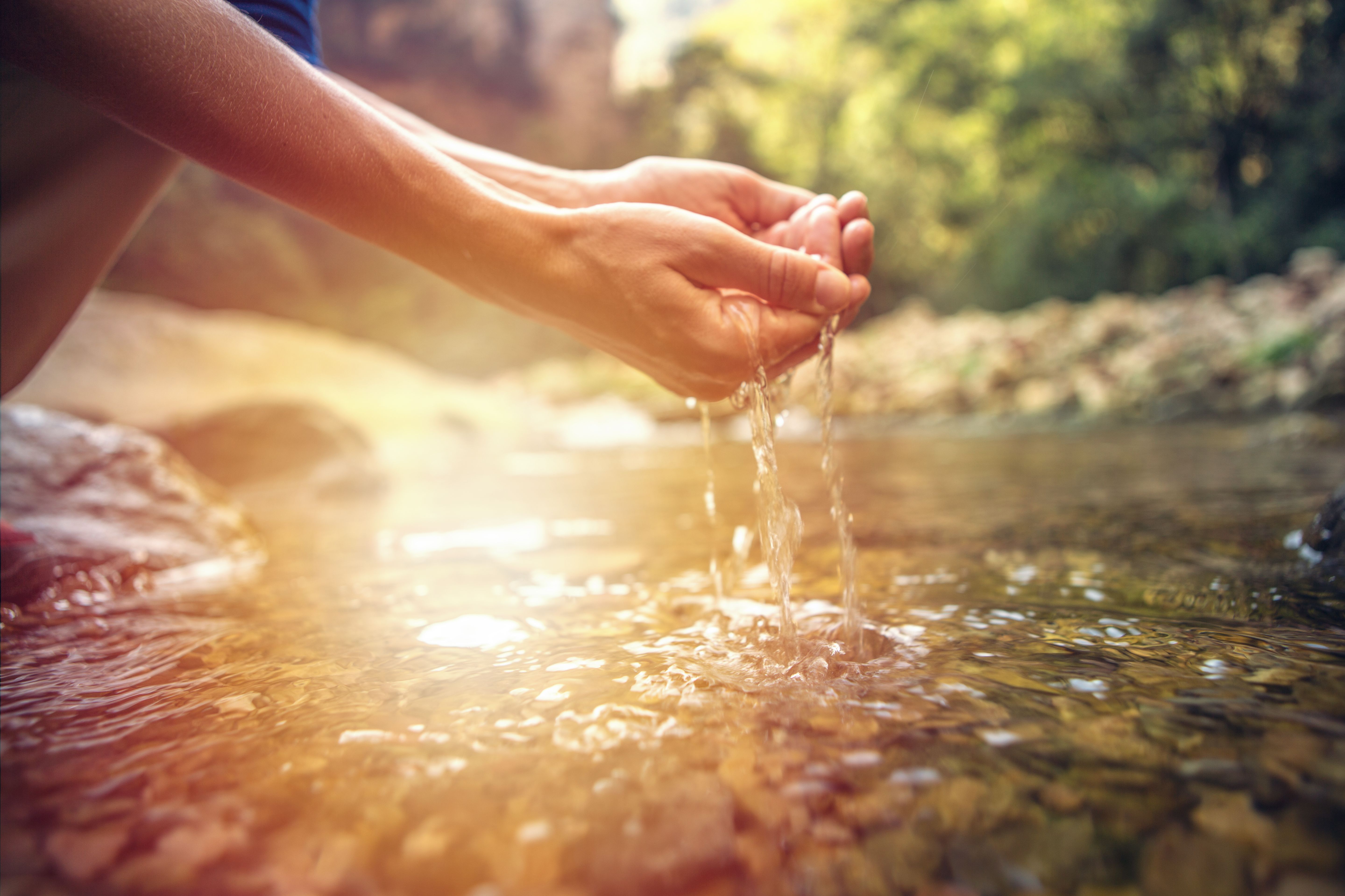 Human hand cupped to catch fresh water from river