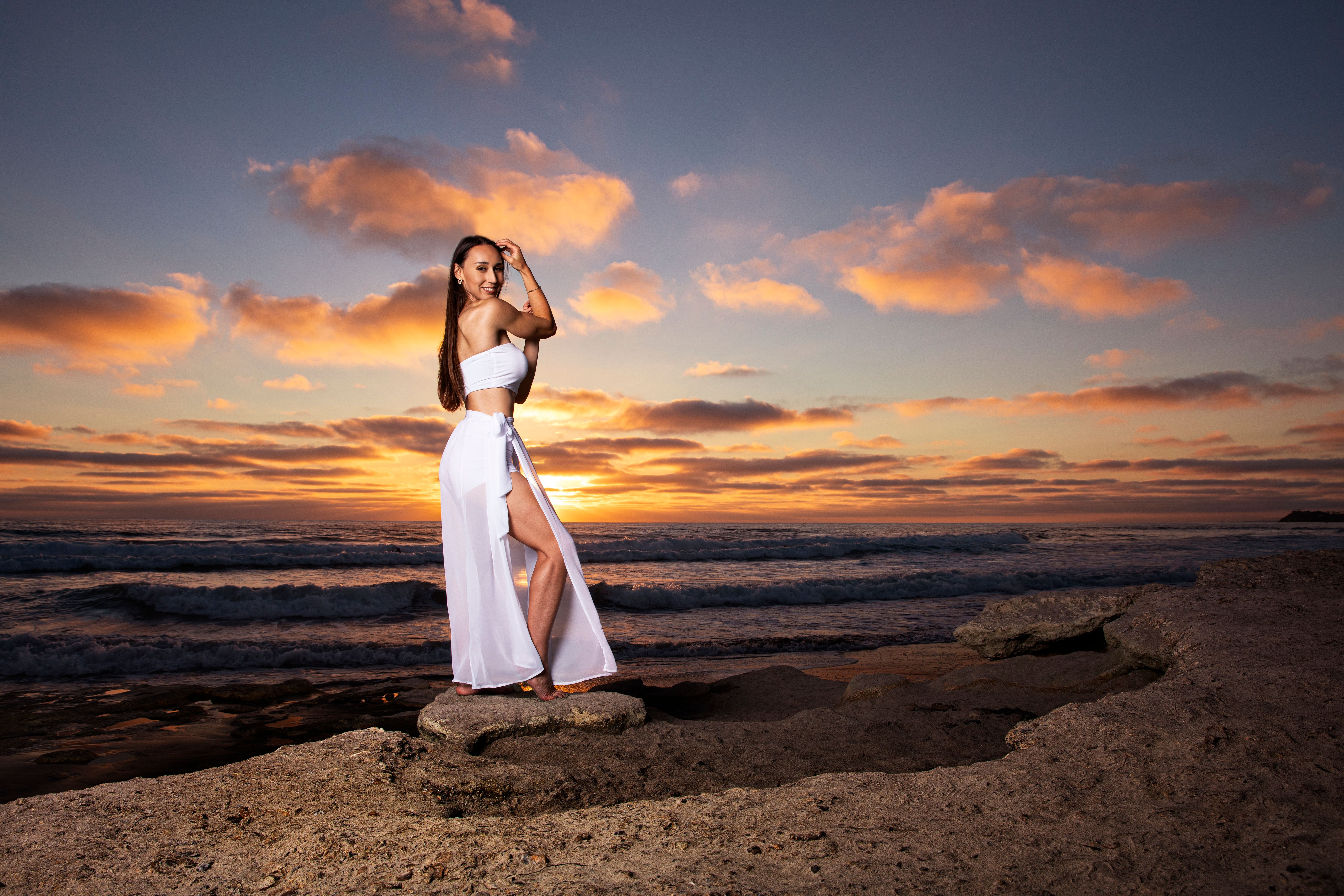 Beautiful brunette girl with long hair in white dress at sunset stock photo