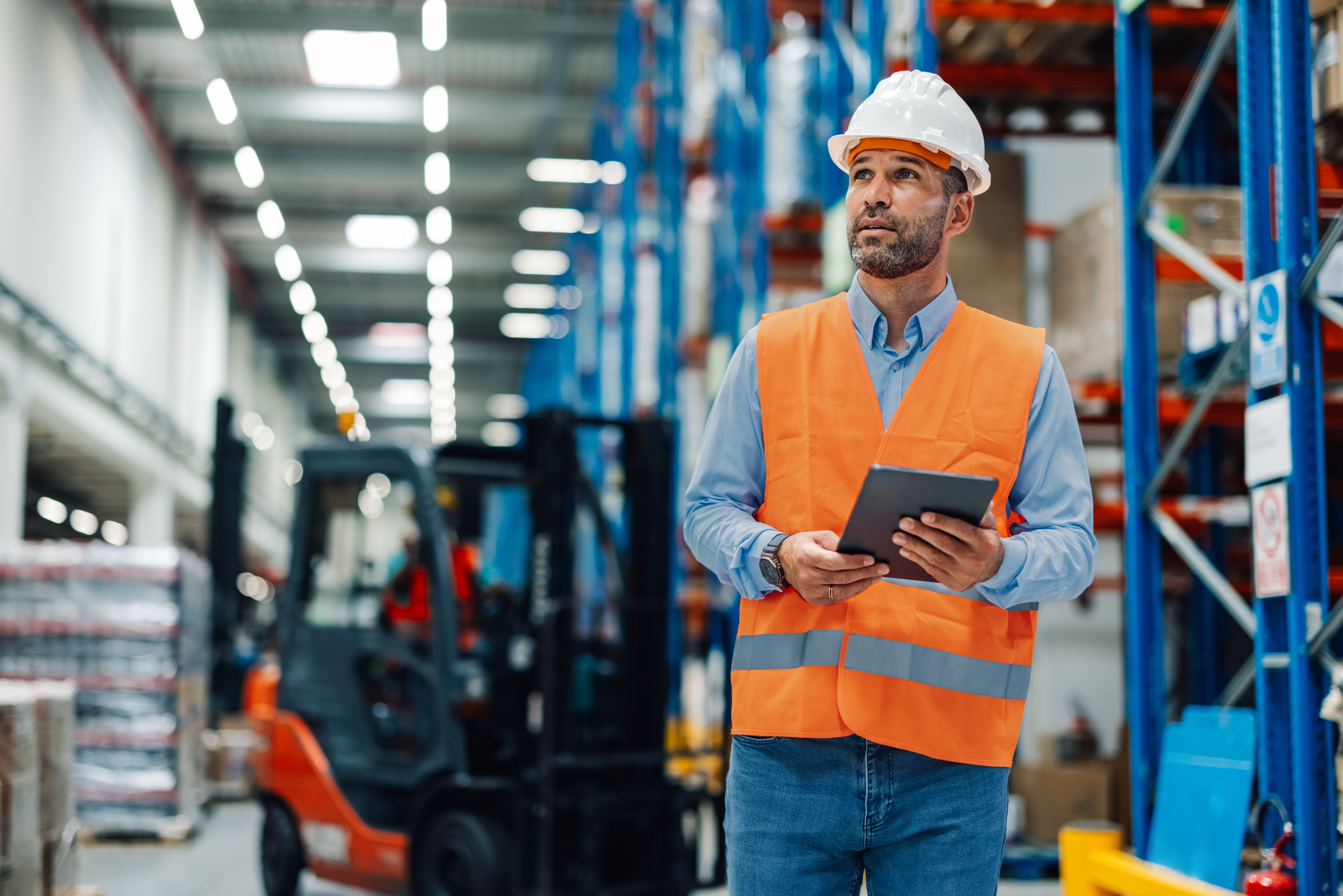 Warehouse manager reviewing digital data amidst stock shelves