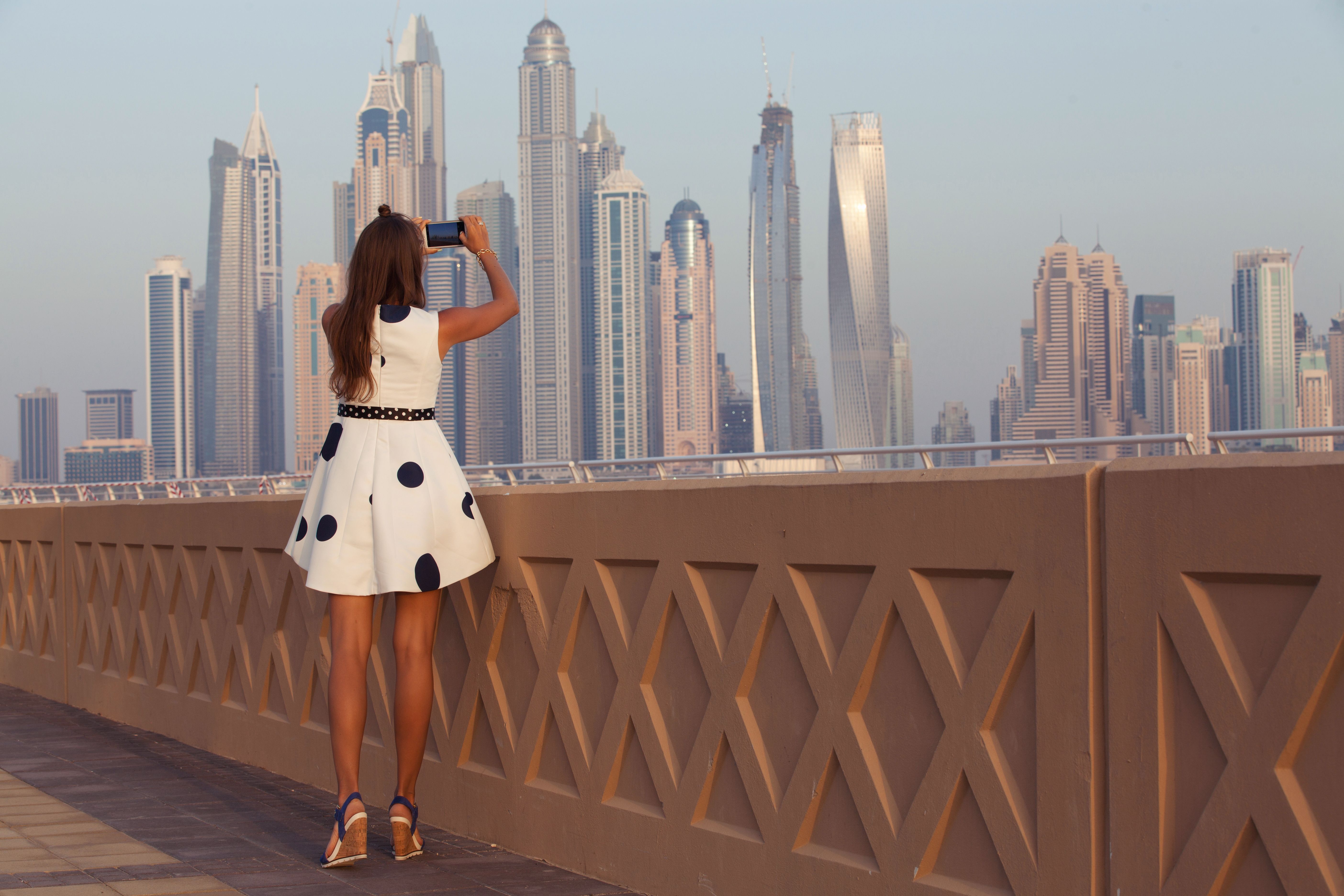 Tourist taking travel picture with phone of Dubai City skyline.